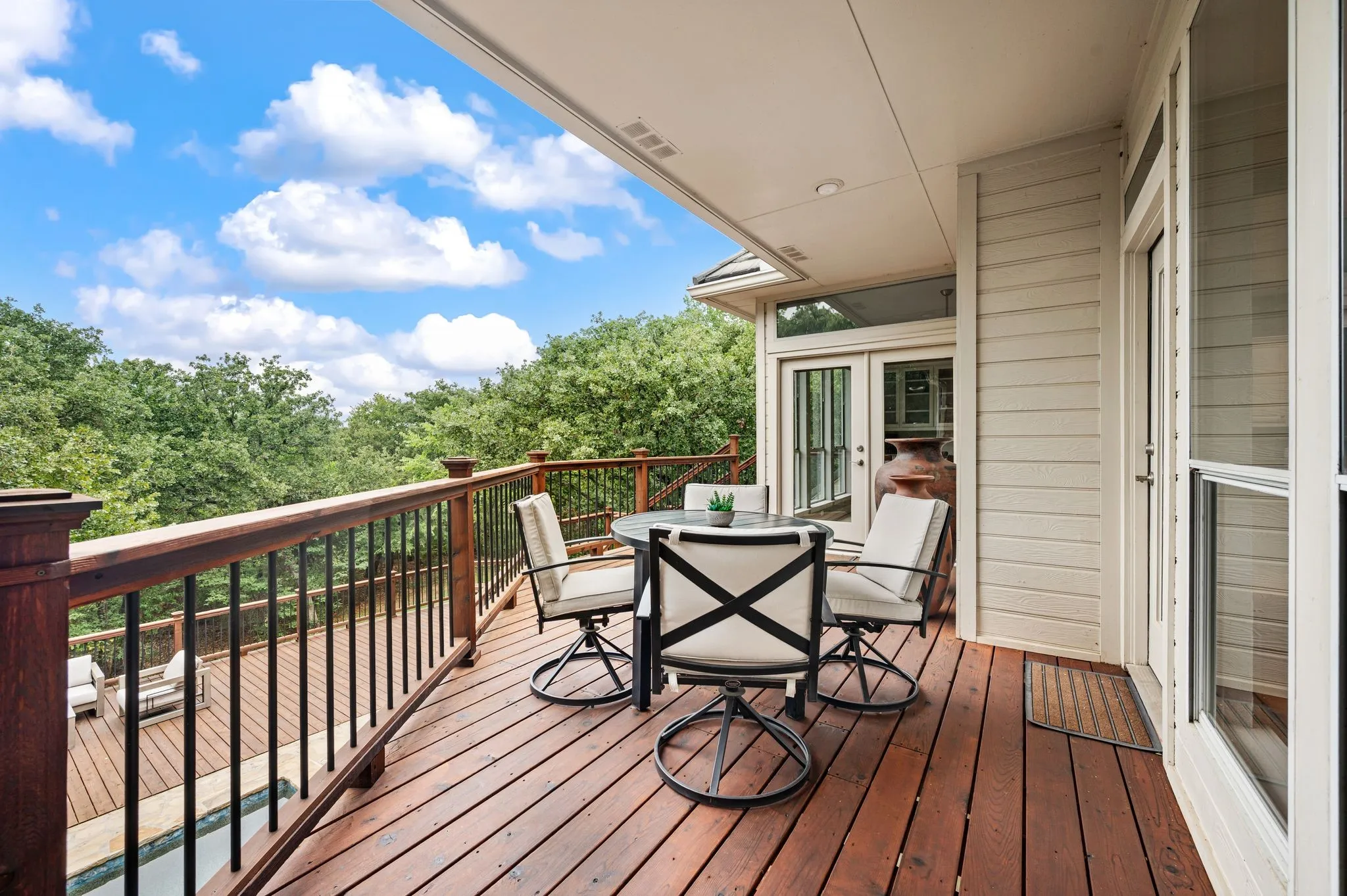 Expansive outdoor deck featuring wood-finish flooring and a wood railing with black metal balusters