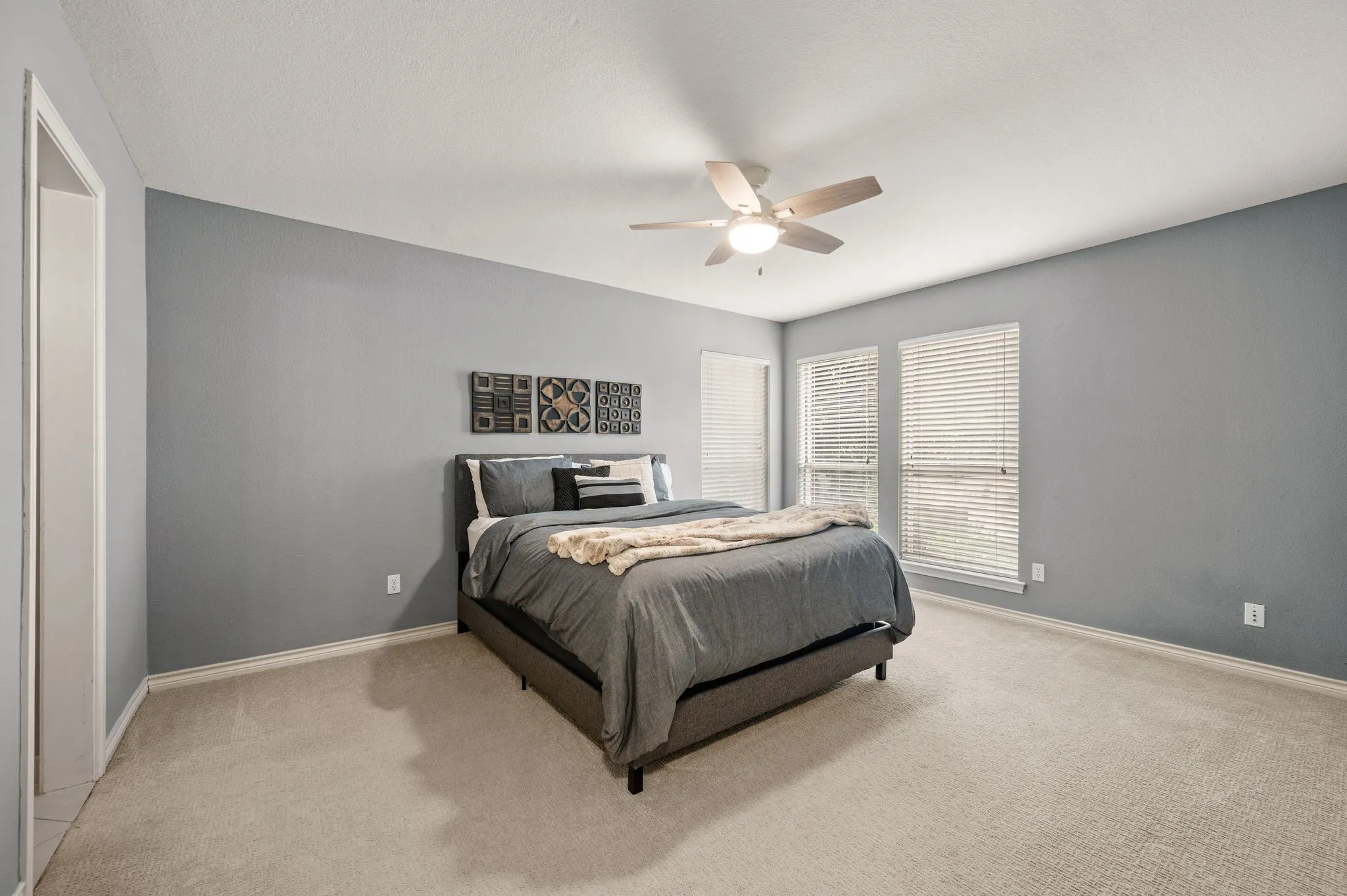 Spacious room featuring light gray walls and plush neutral carpeting