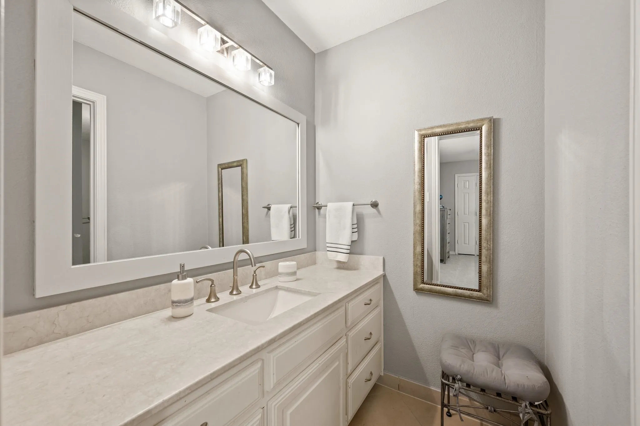 White framed mirror above a dual-basin vanity with a light-colored countertop