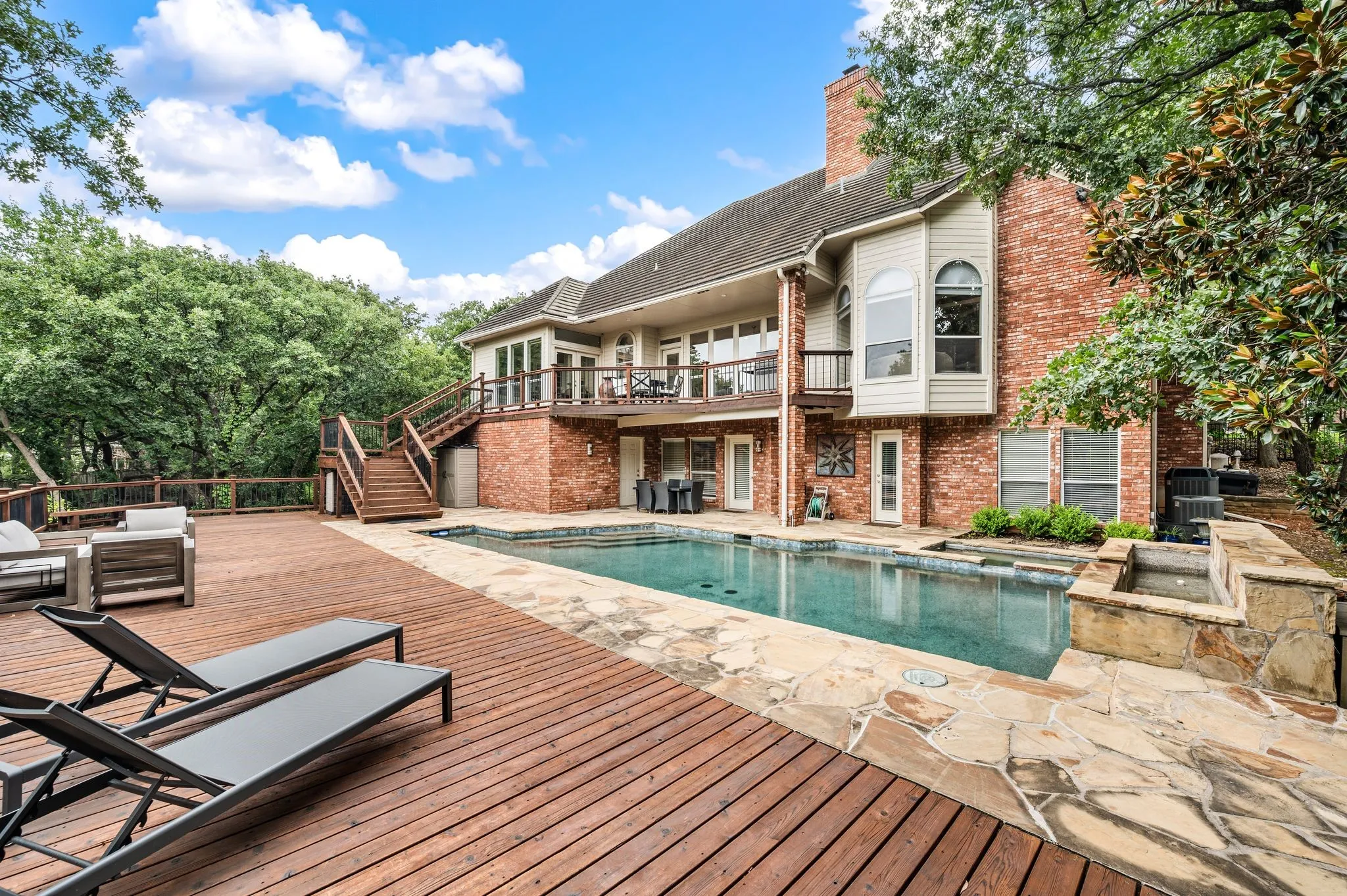 Expansive wood deck with a built-in swimming pool and integrated spa