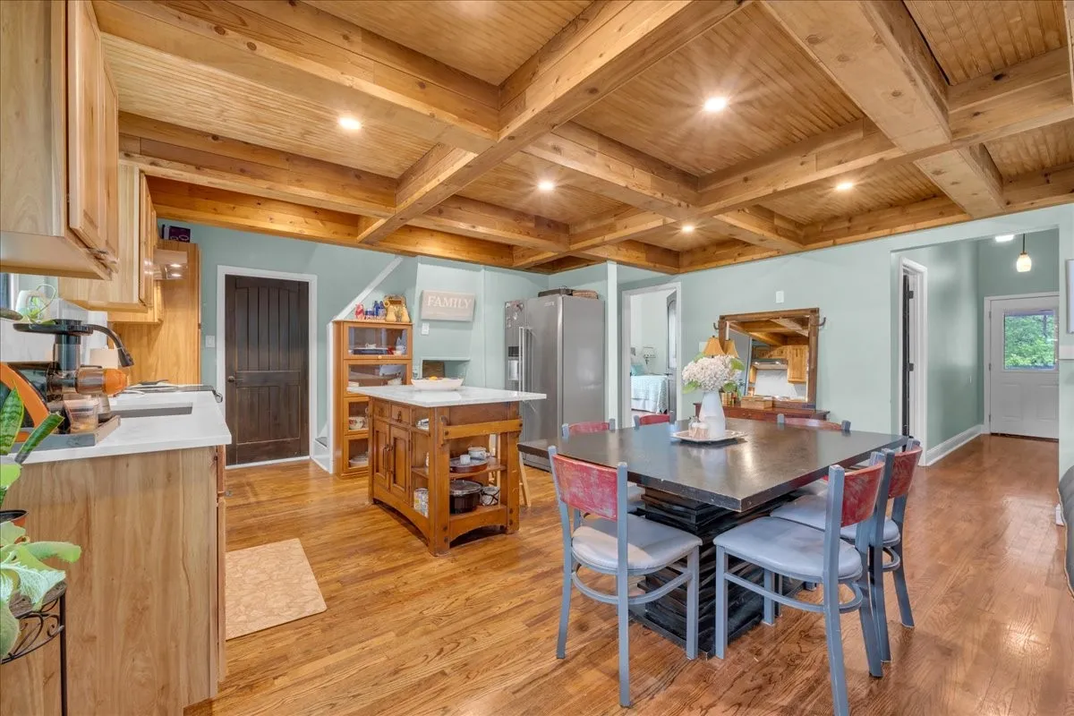 Kitchen area featuring wood-finish flooring, a coffered wood-paneled ceiling with recessed lighting, light wood cabinetry, a central island, and a separate dining space