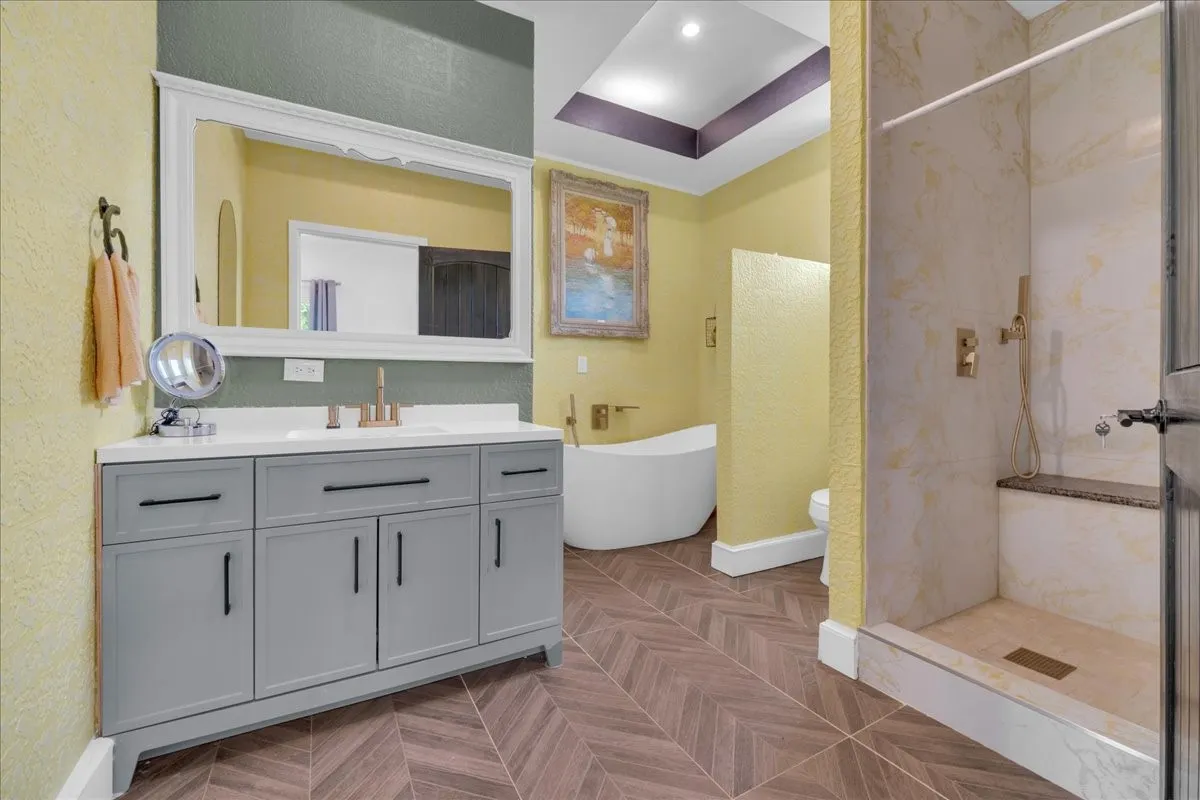Spacious bath featuring a freestanding tub, walk-in shower with built-in bench, and a large vanity with ample storage