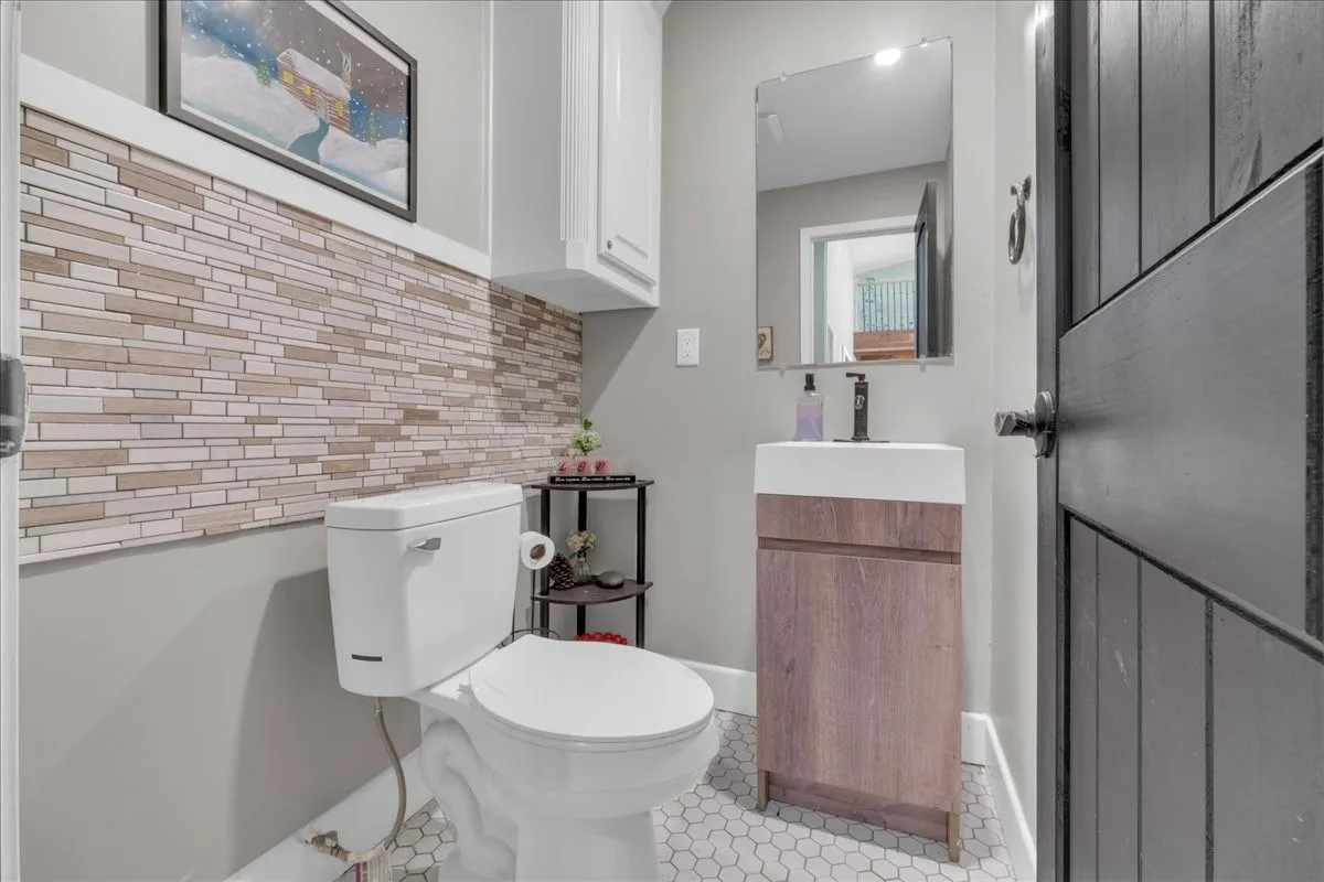 Powder room featuring a modern floating vanity with a vessel sink, a matte black faucet, and hexagon tile flooring