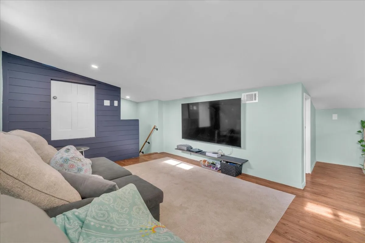 Finished living area featuring wood-finish flooring, light-toned walls, and recessed lighting