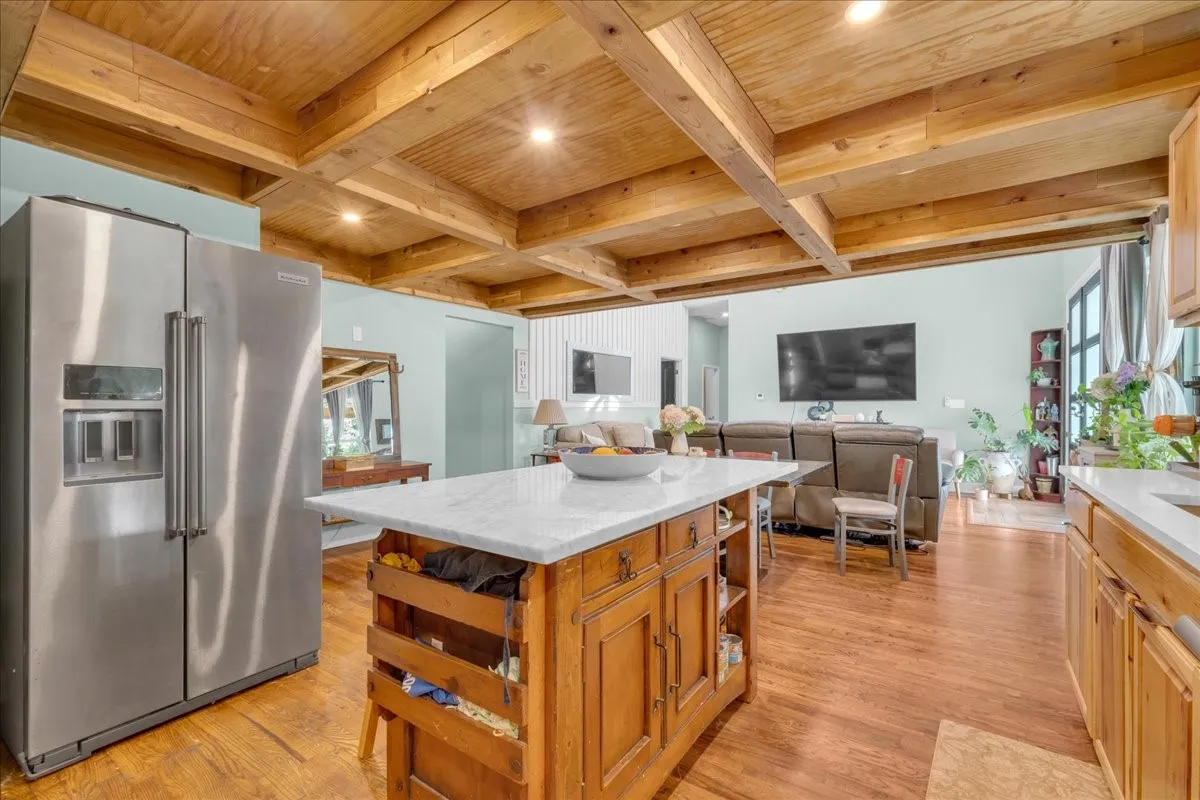 Kitchen featuring a large stainless steel side-by-side refrigerator, a wood-finish island with a light-colored countertop, and recessed lighting