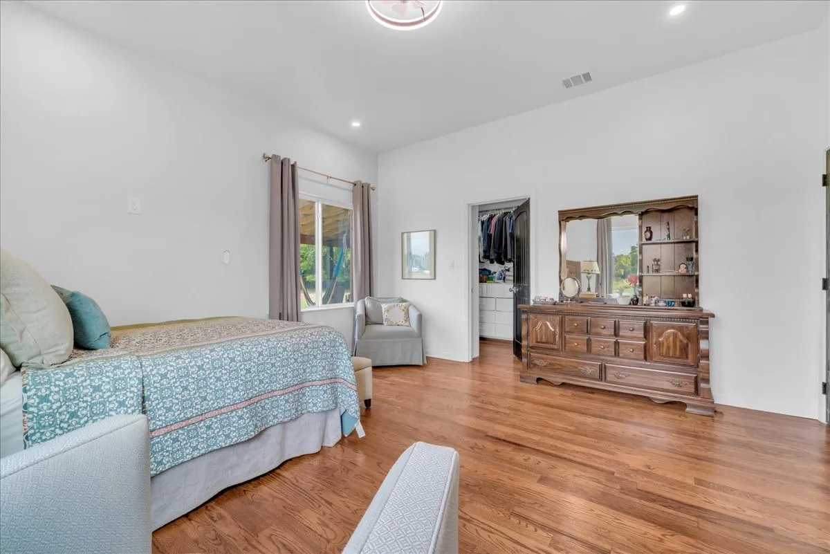 Bright room featuring wood-finish flooring, a window with outdoor visibility, and a walk-in closet