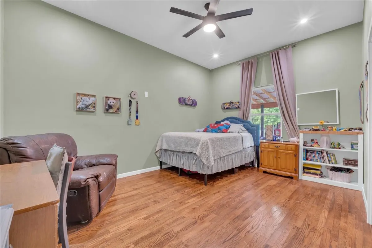 Bedroom featuring high ceilings, wood-finish flooring, recessed lighting, a ceiling fan, and window with exterior exposure