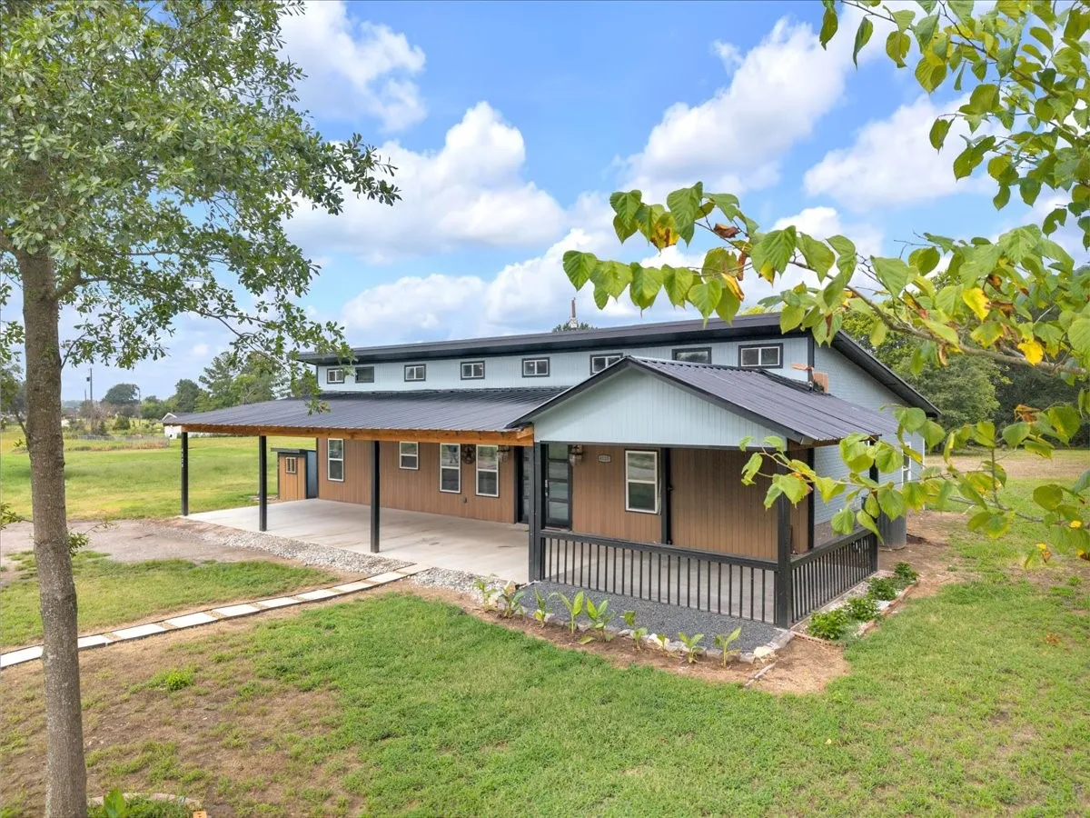 Modern farmhouse exterior featuring an expansive covered porch, metal roof, and durable siding