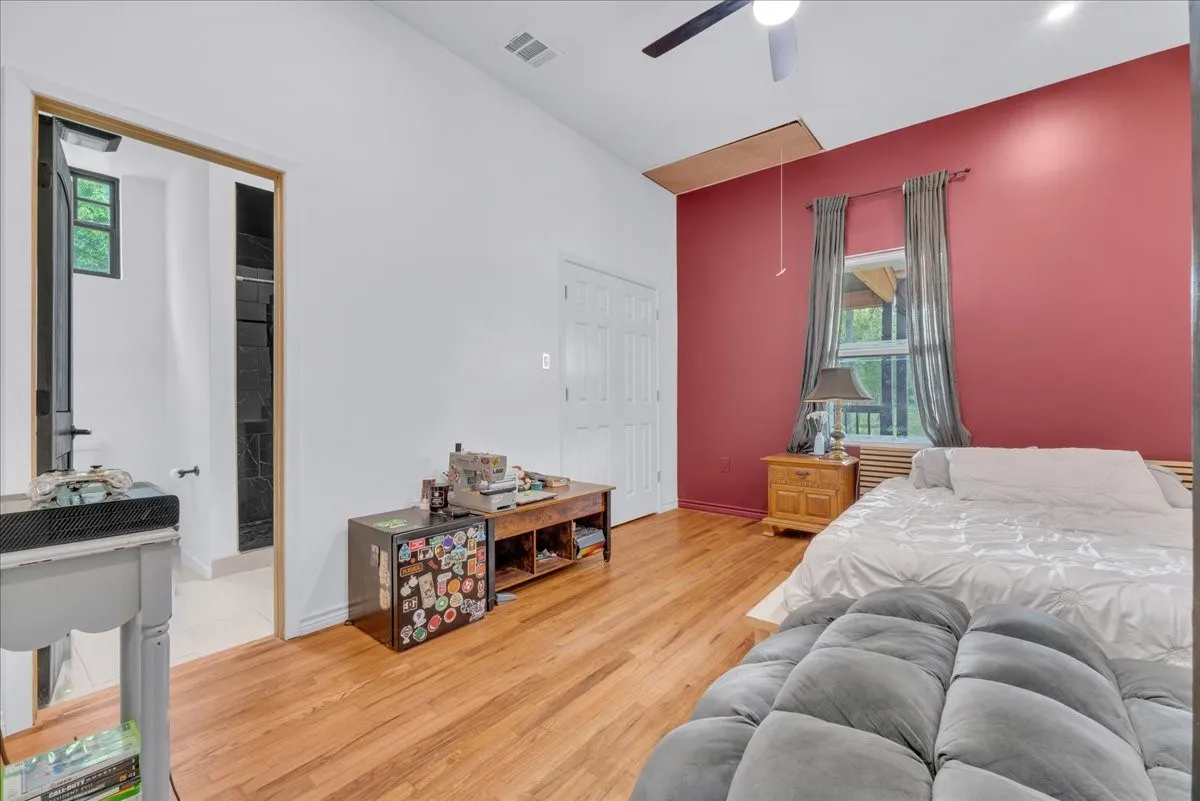 Spacious room featuring wood-finish flooring, a ceiling fan, and a window providing natural light