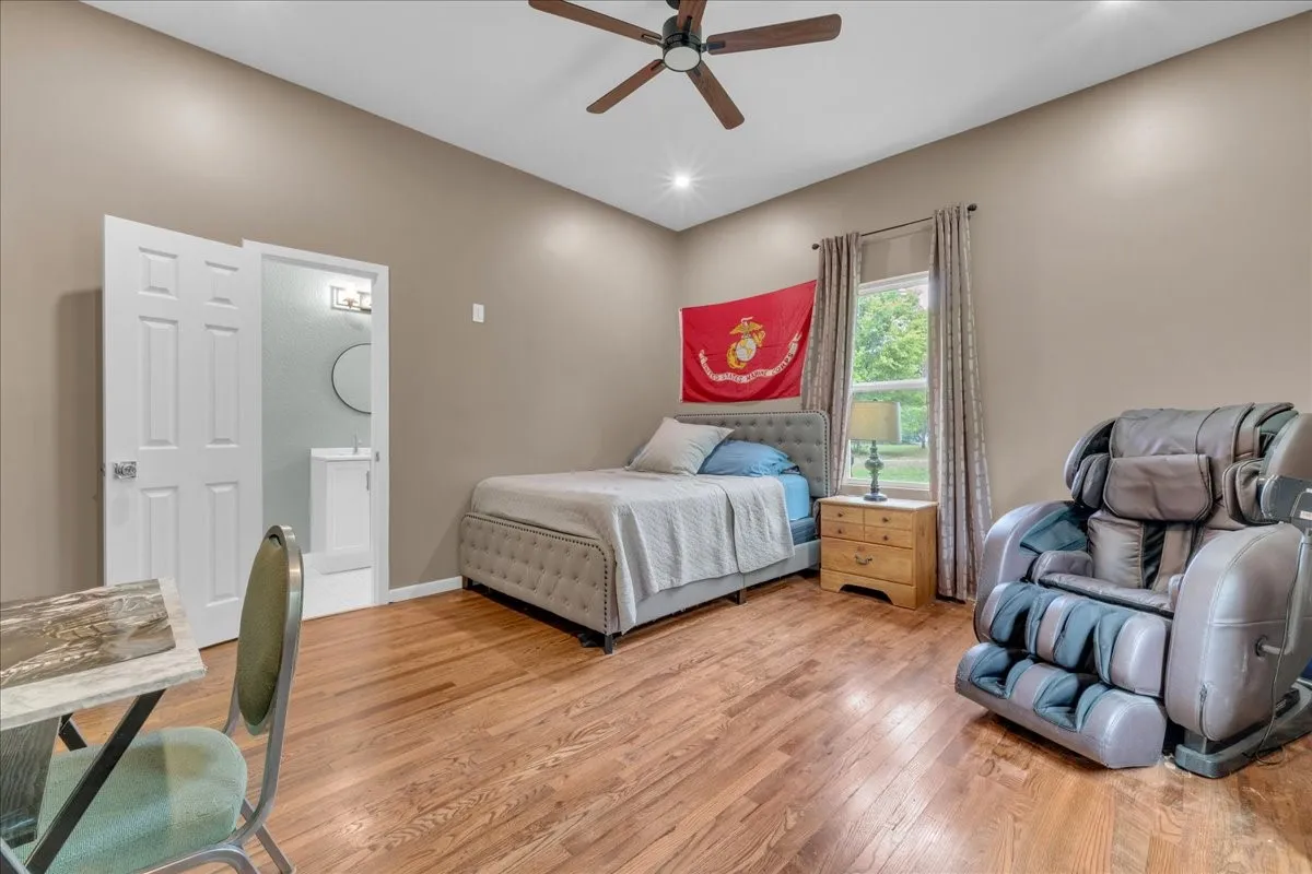 Room featuring high ceilings, wood-finish flooring, a ceiling fan with integrated lighting, and a window with curtains