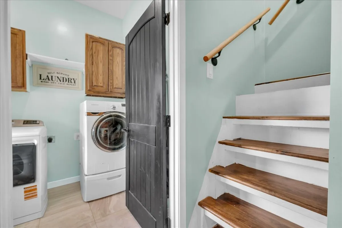 Dedicated laundry area featuring light blue walls, wood-finish cabinetry, and tiled flooring