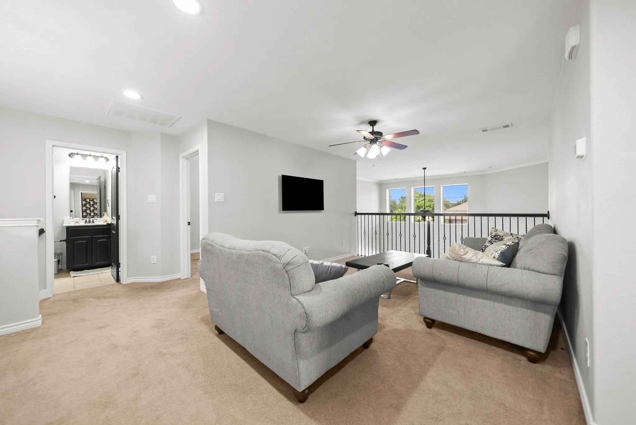 Carpeted loft area featuring a ceiling fan, recessed lighting, and a black metal railing overlooking a lower level