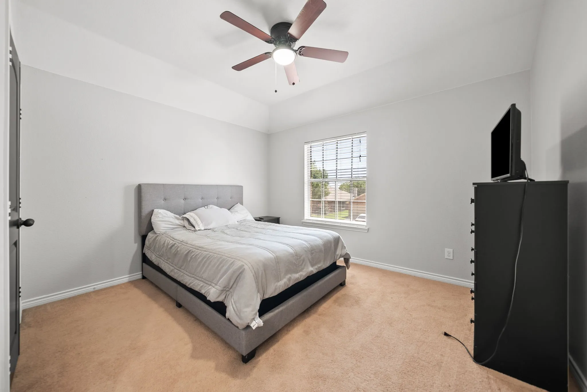 Carpeted bedroom featuring a vaulted ceiling with a ceiling fan, a window with horizontal blinds, and neutral-toned walls