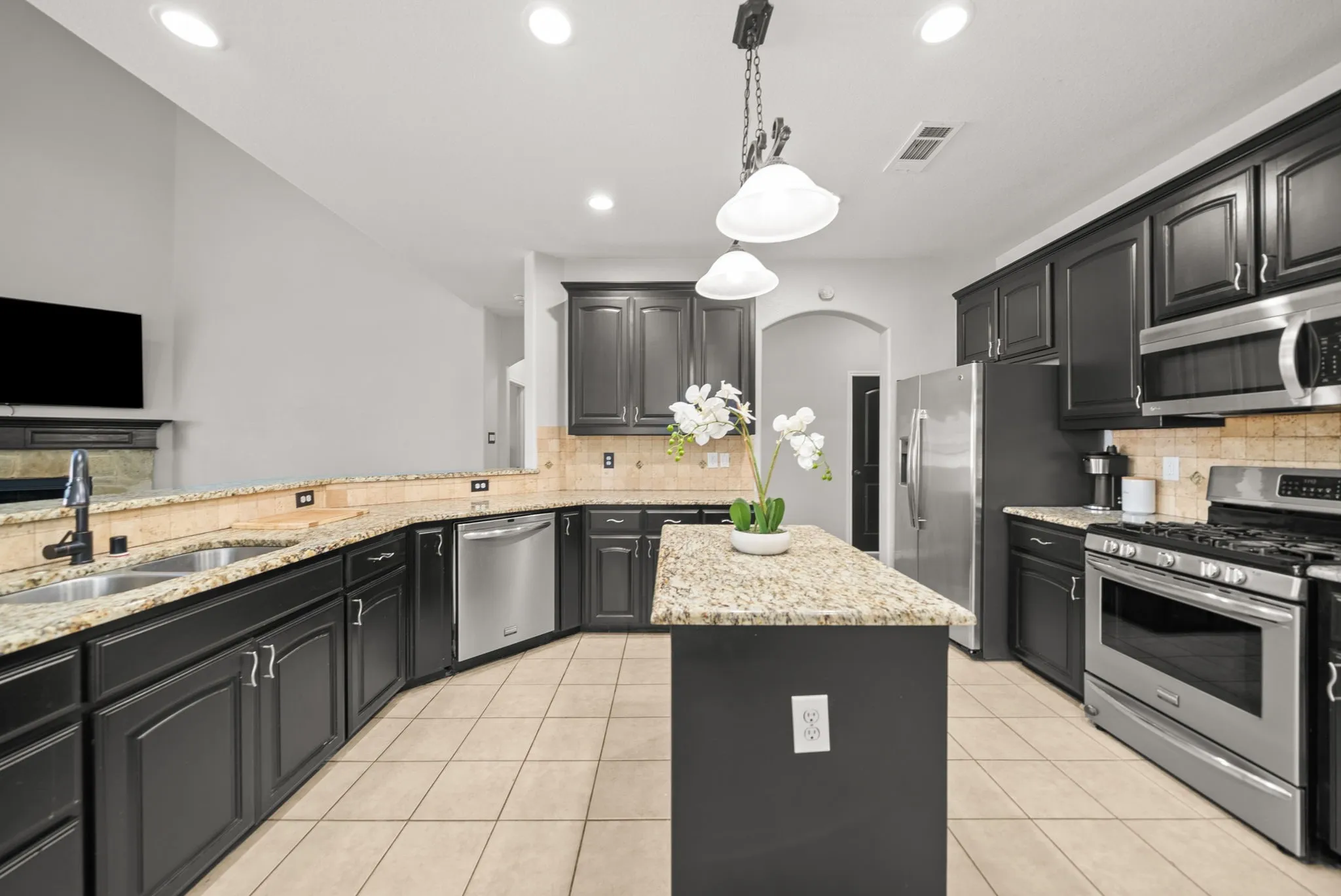 Spacious kitchen featuring dark cabinetry, granite countertops, and stainless steel appliances