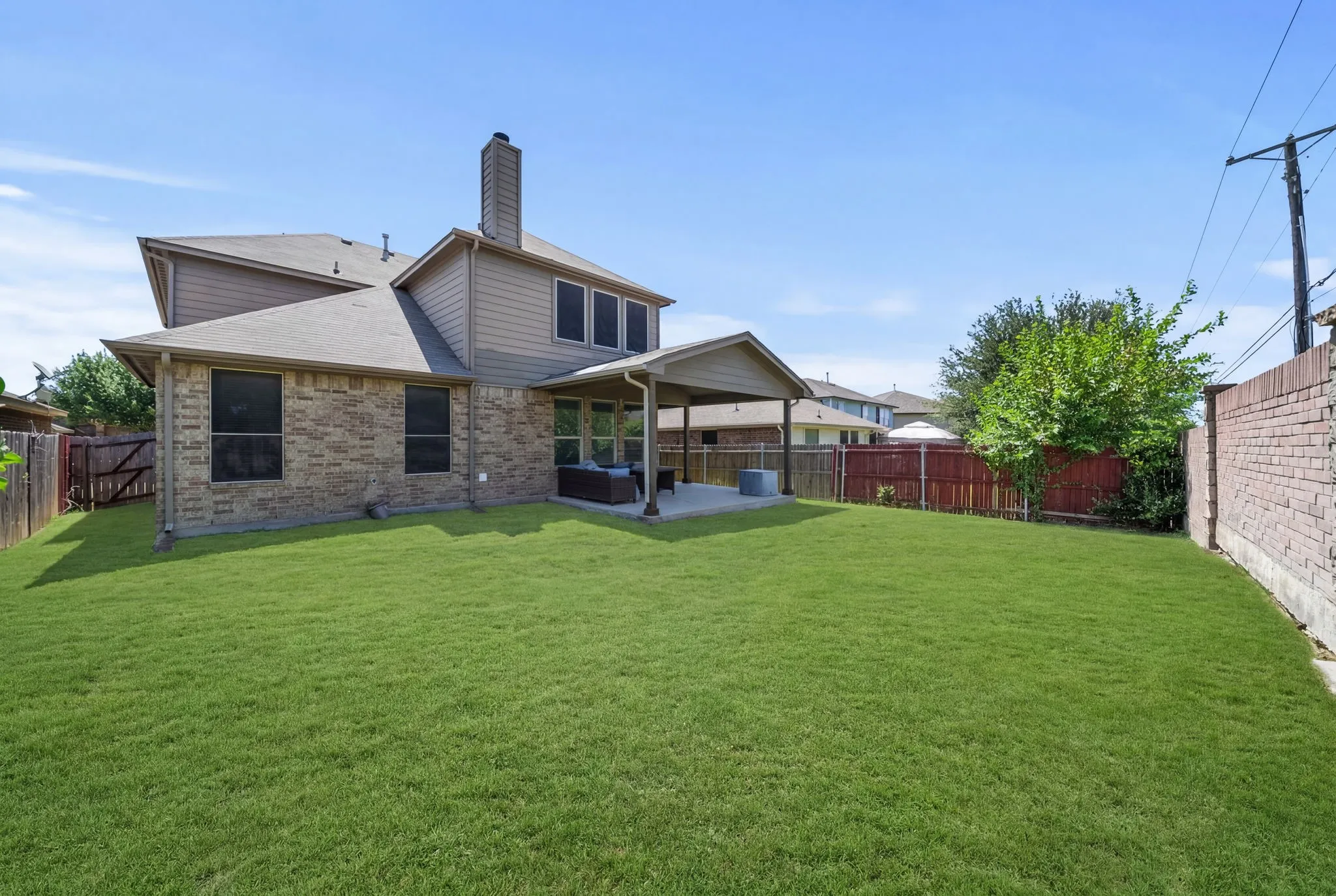 Expansive green lawn with a covered patio area