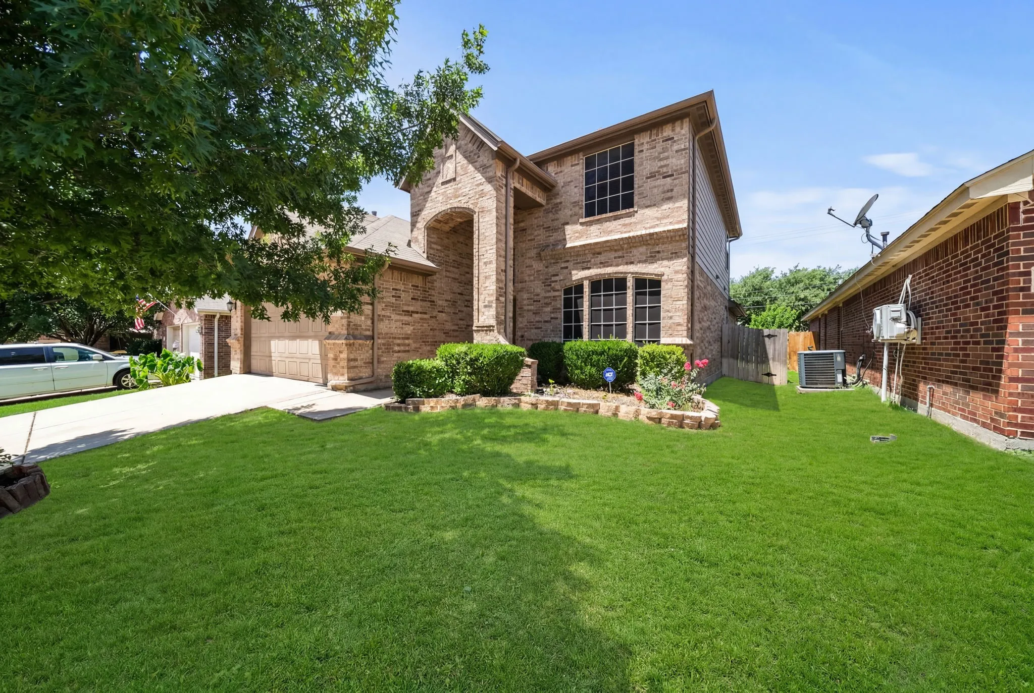 Brick two-story facade featuring arched entry, multiple window styles, and an attached two-car garage