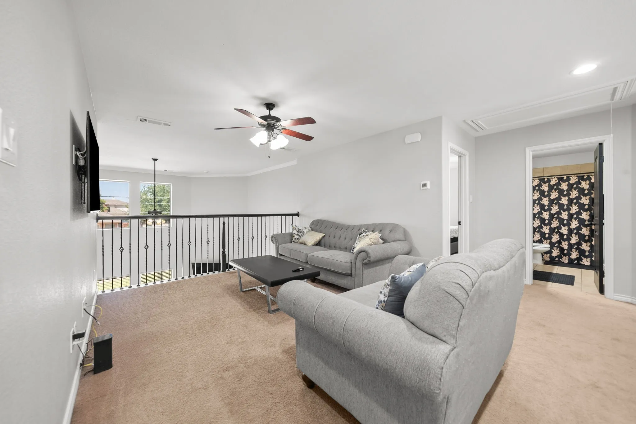 Carpeted loft area featuring a metal baluster railing, an overhead ceiling fan, and recessed lighting