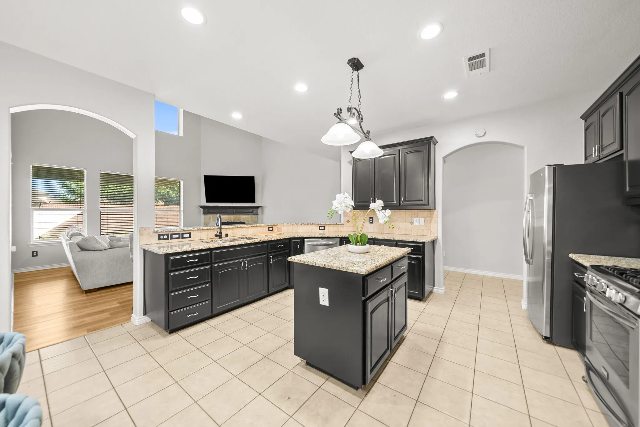 Kitchen featuring dark cabinetry, granite countertops, and a central island with pendant lighting