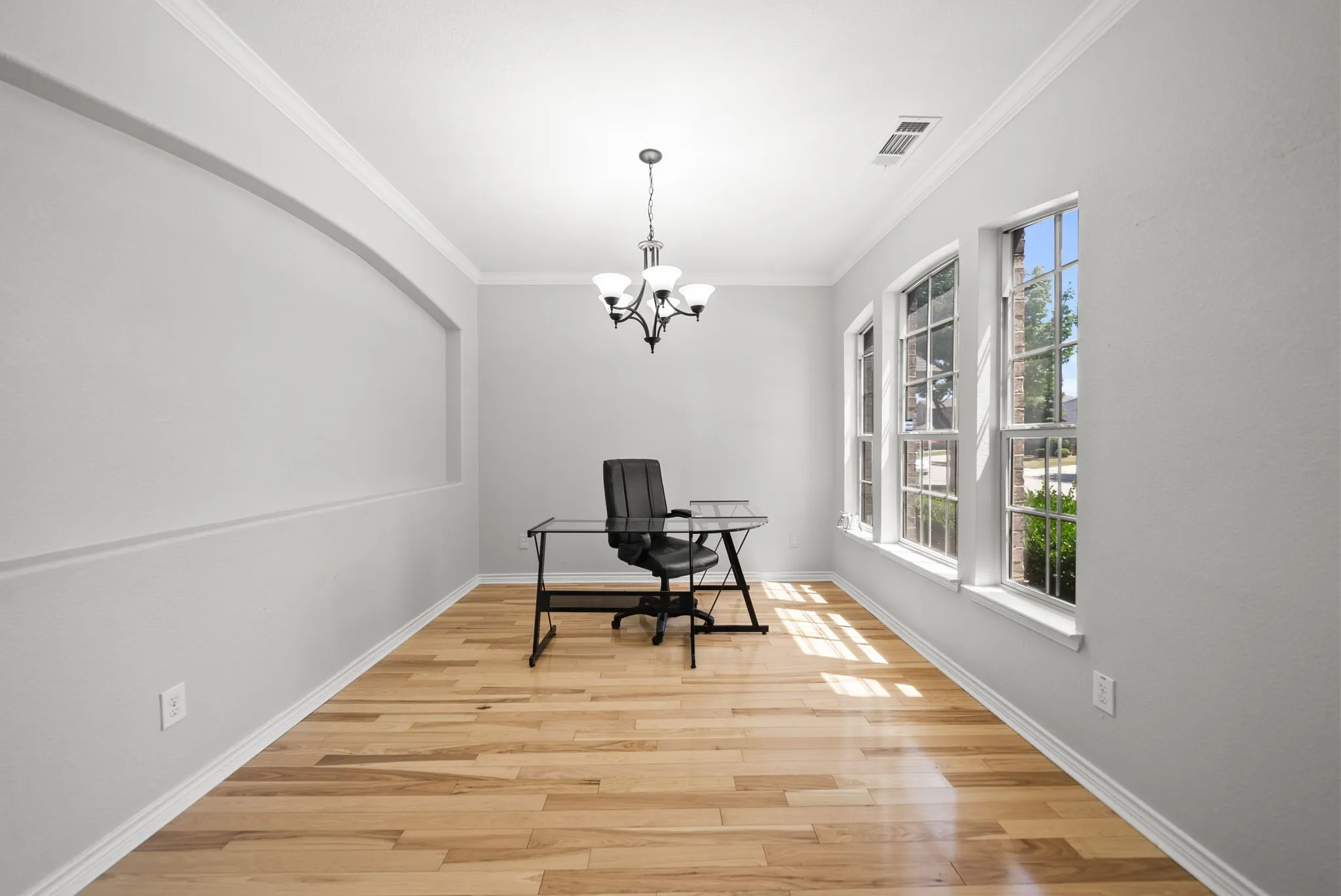 Bright room with wood-finish flooring and three large windows