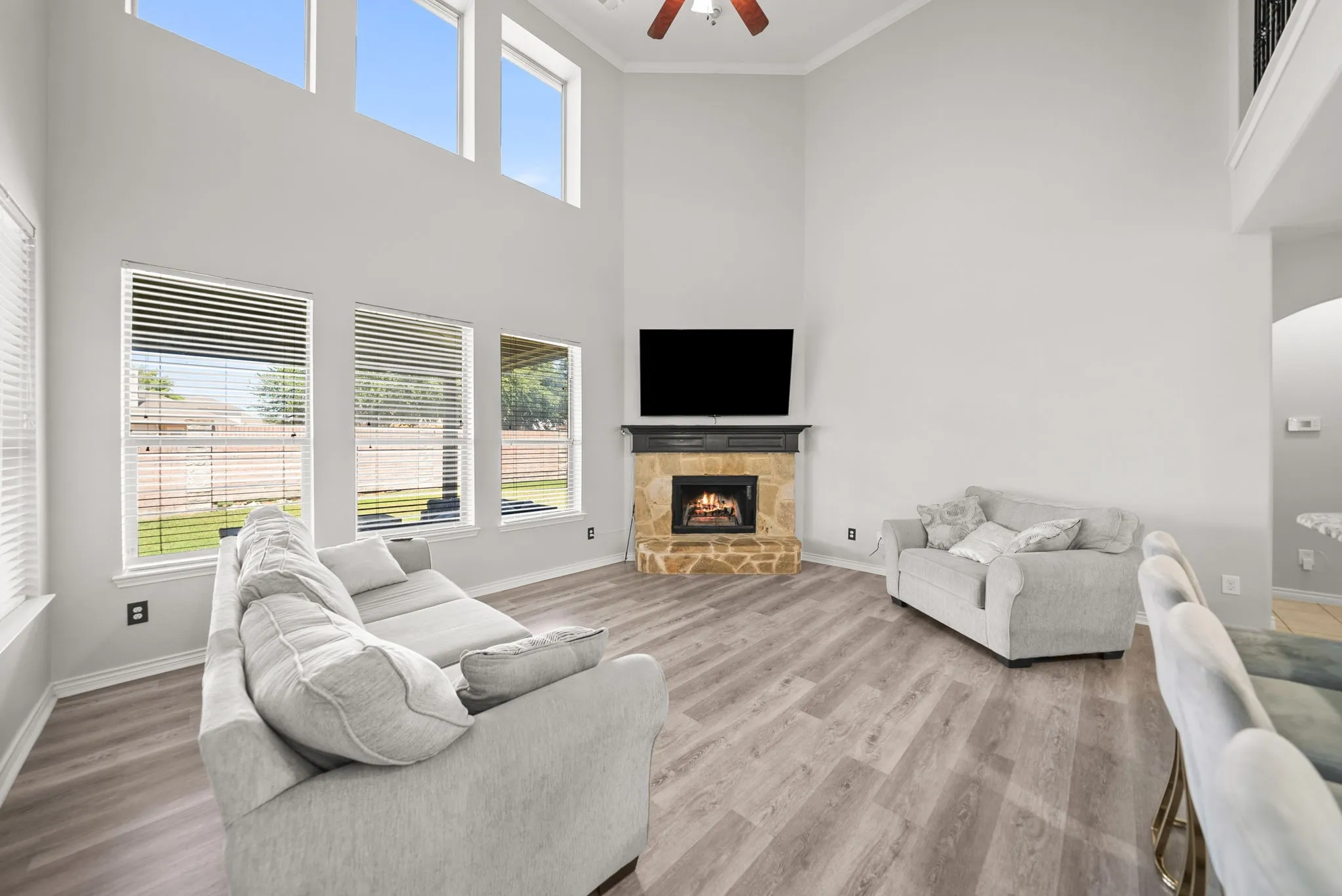 Vaulted ceiling living area featuring wood-finish flooring and a stone-clad fireplace