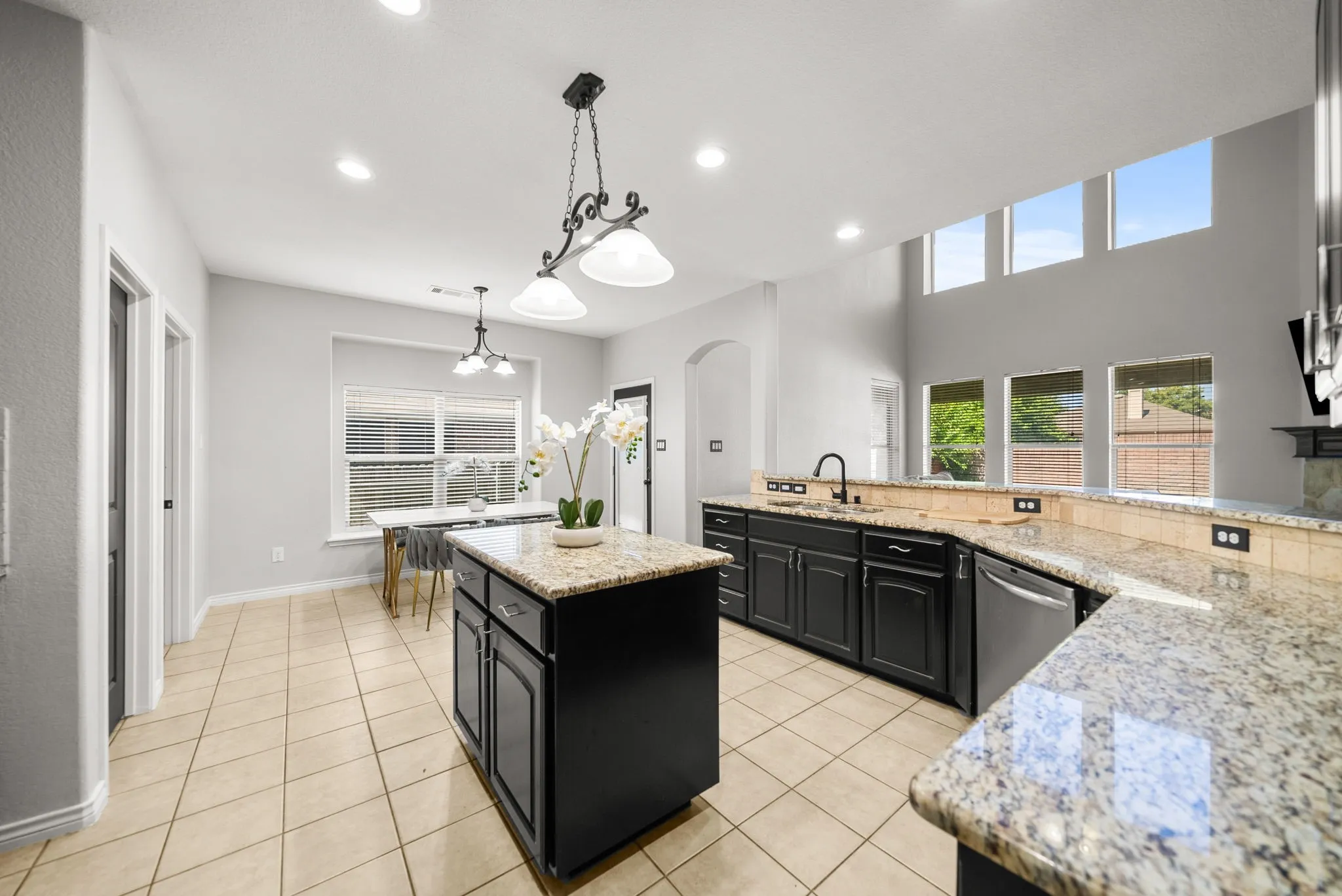 Spacious kitchen featuring an island, extensive granite countertops, dark cabinetry, and tile flooring