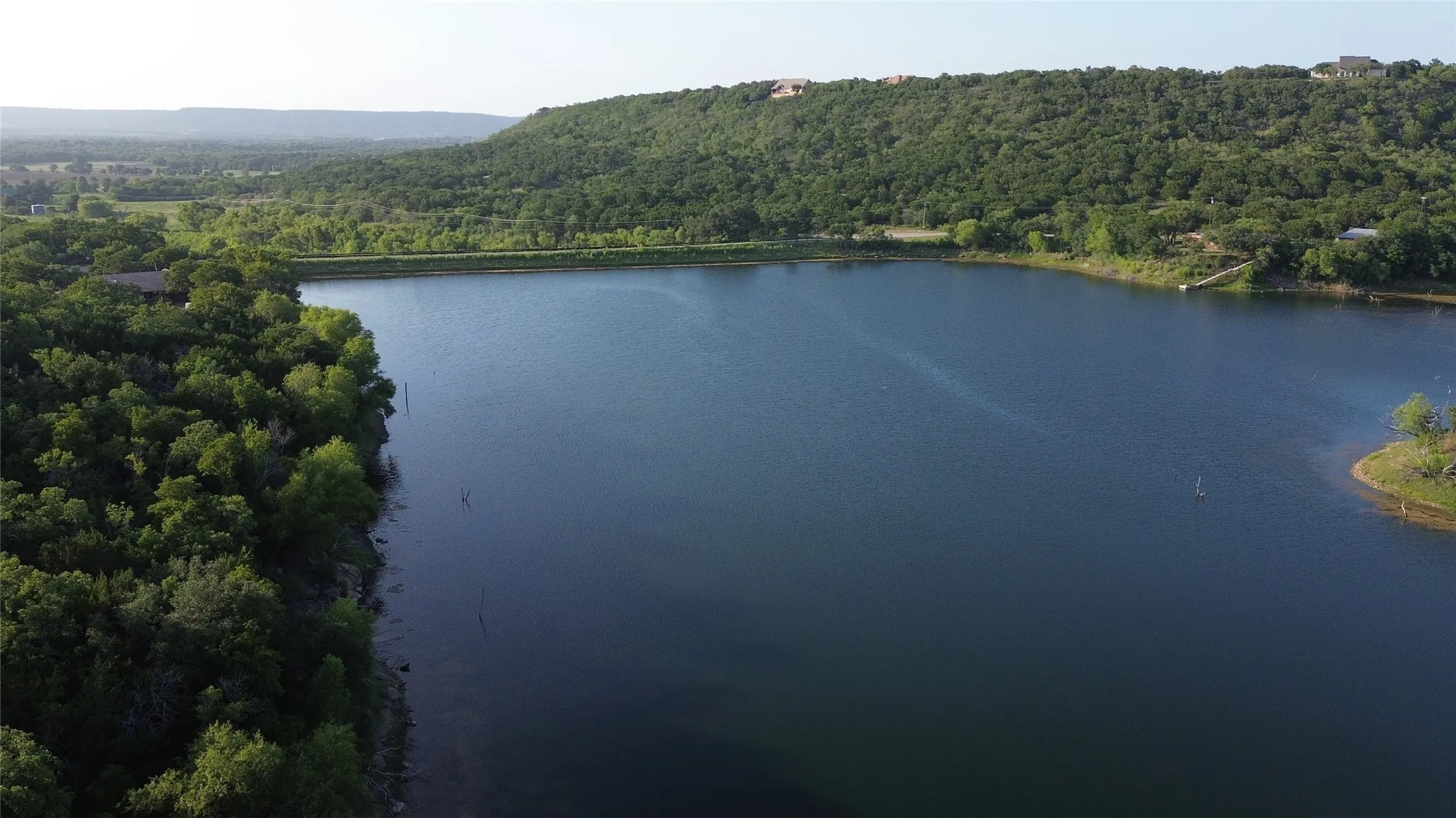 Expansive lakefront setting with a natural shoreline and surrounding mature trees