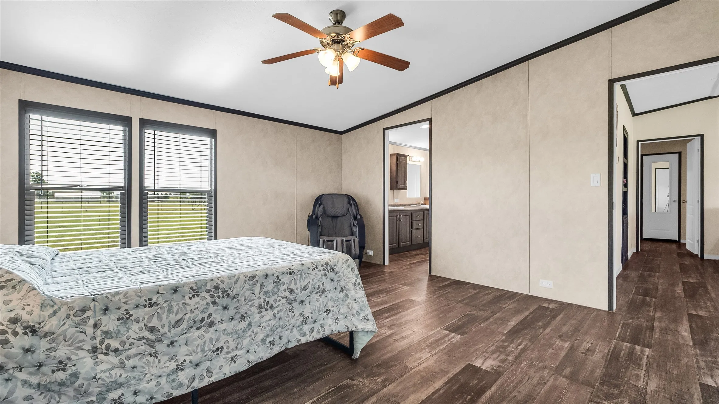 Spacious interior featuring laminate flooring, two large windows with horizontal blinds, and a ceiling fan with integrated lighting