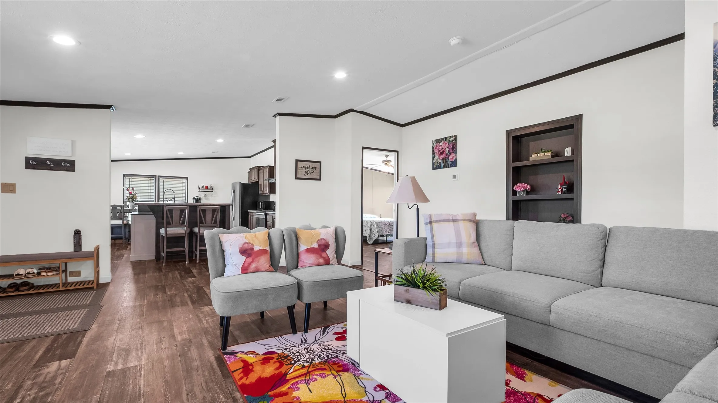 Open-concept living area featuring laminate flooring, recessed lighting, and contrasting dark trim