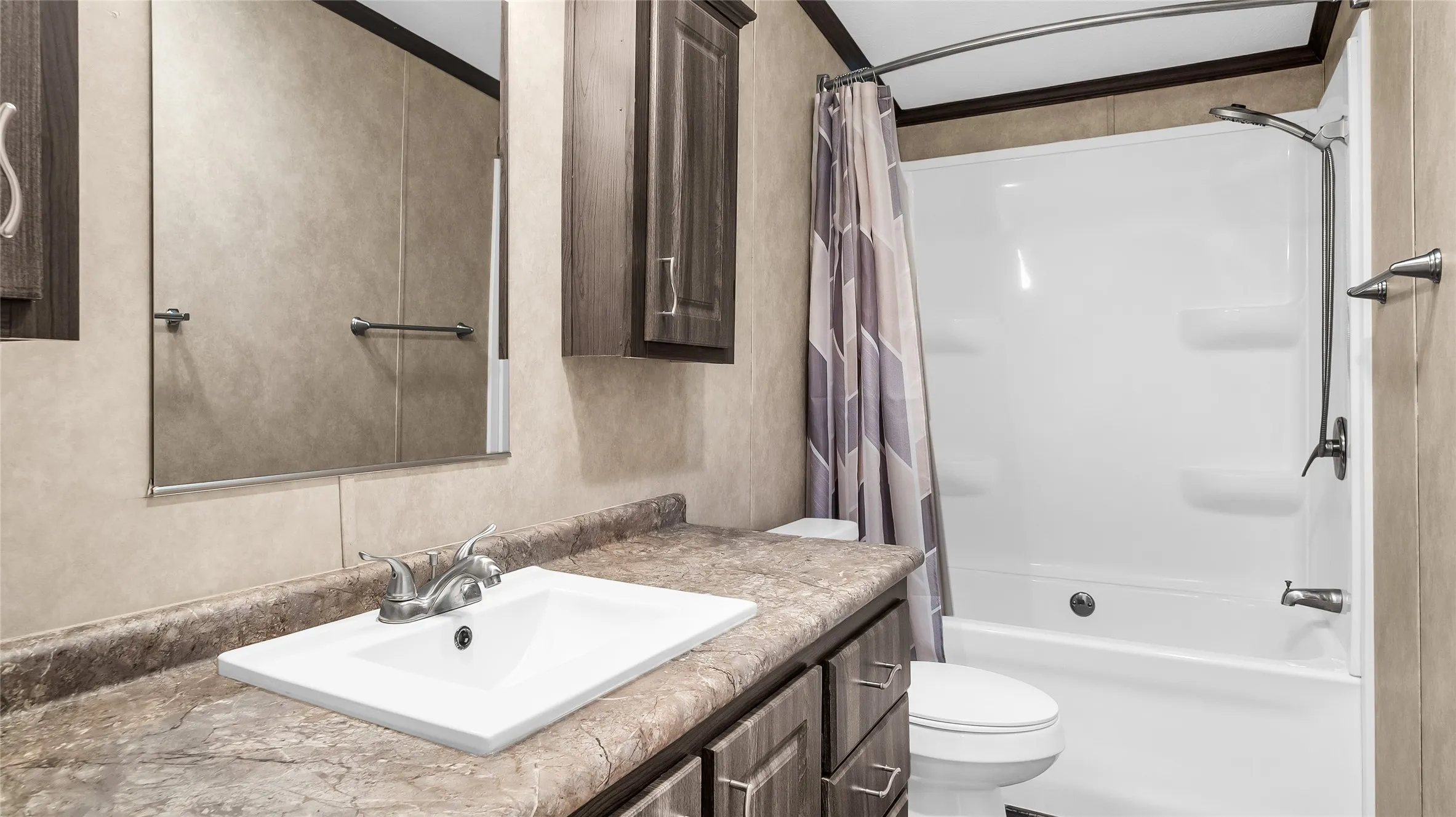 Bathroom featuring a white ceramic sink with brushed nickel faucet, a spacious vanity with a stone-finish countertop, and dark wood-finish cabinetry