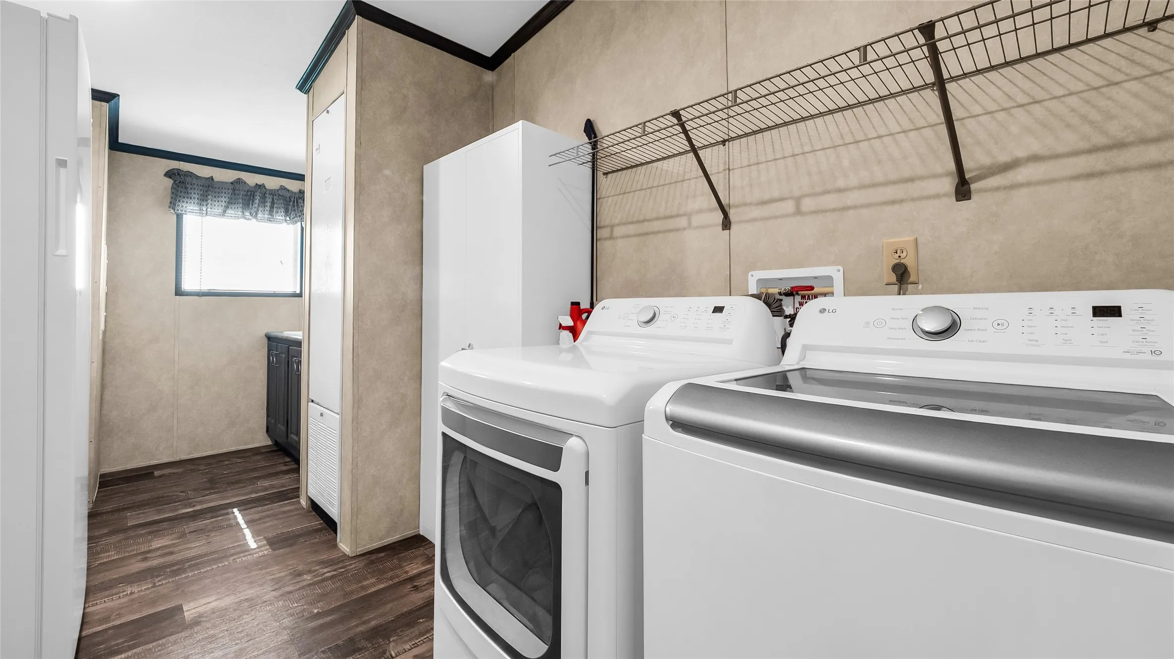 Dedicated laundry area featuring laminate flooring, a mounted wire shelf, and a window