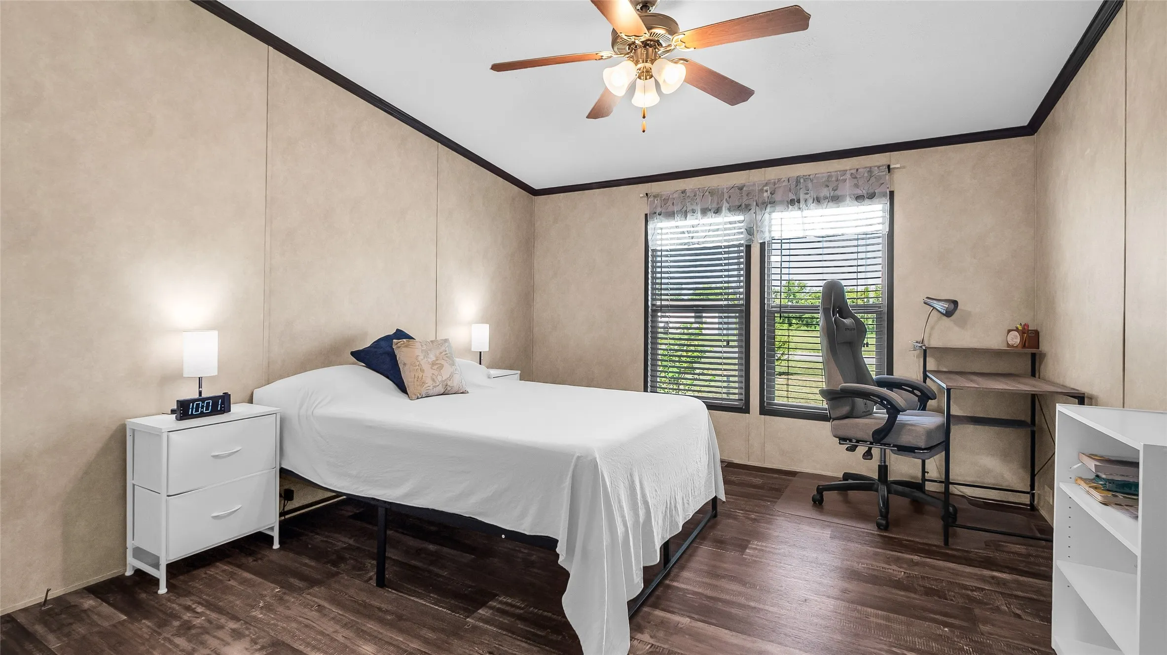 Bedroom featuring laminate flooring, two large windows with blinds, and a ceiling fan with integrated lighting