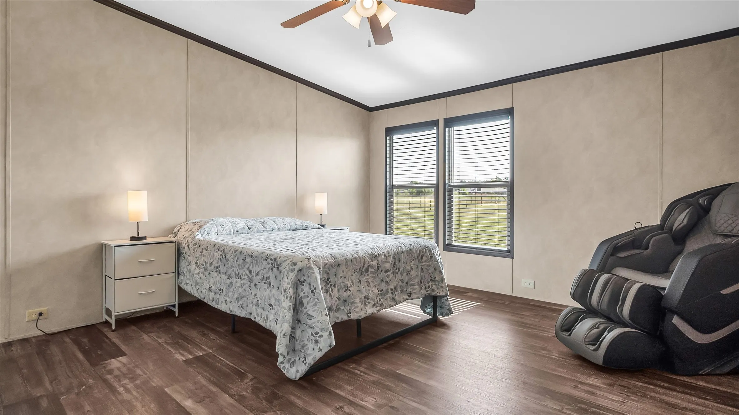 Spacious room featuring laminate flooring, two windows with blinds, and a ceiling fan with integrated lighting