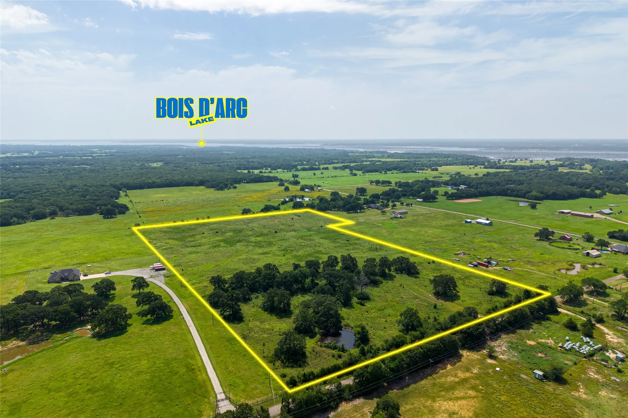 Aerial shot of 27+ acres with mature trees, pond, and open pasture looking NW