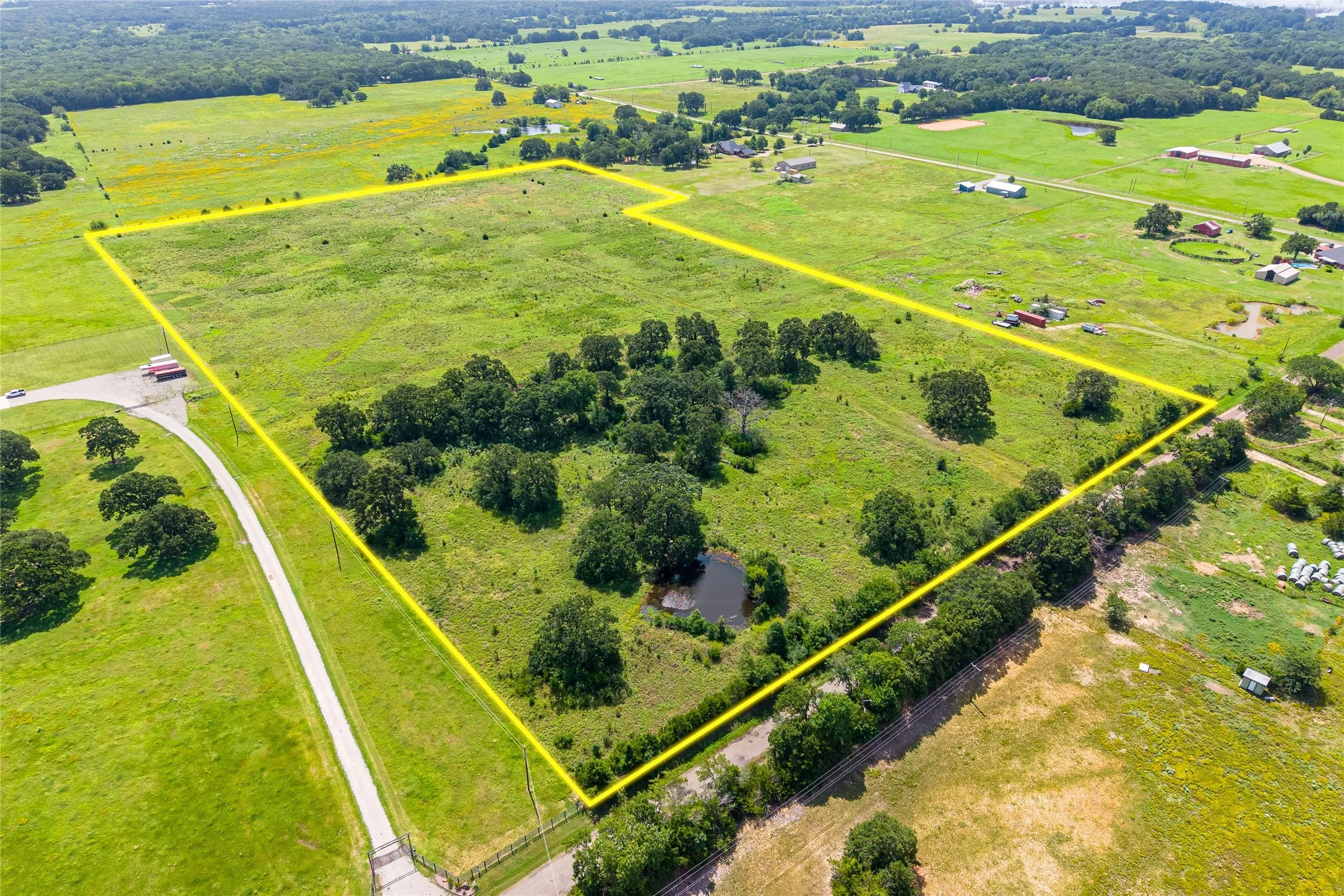 Aerial shot of 27+ acres with mature trees, pond, and open pasture looking NW