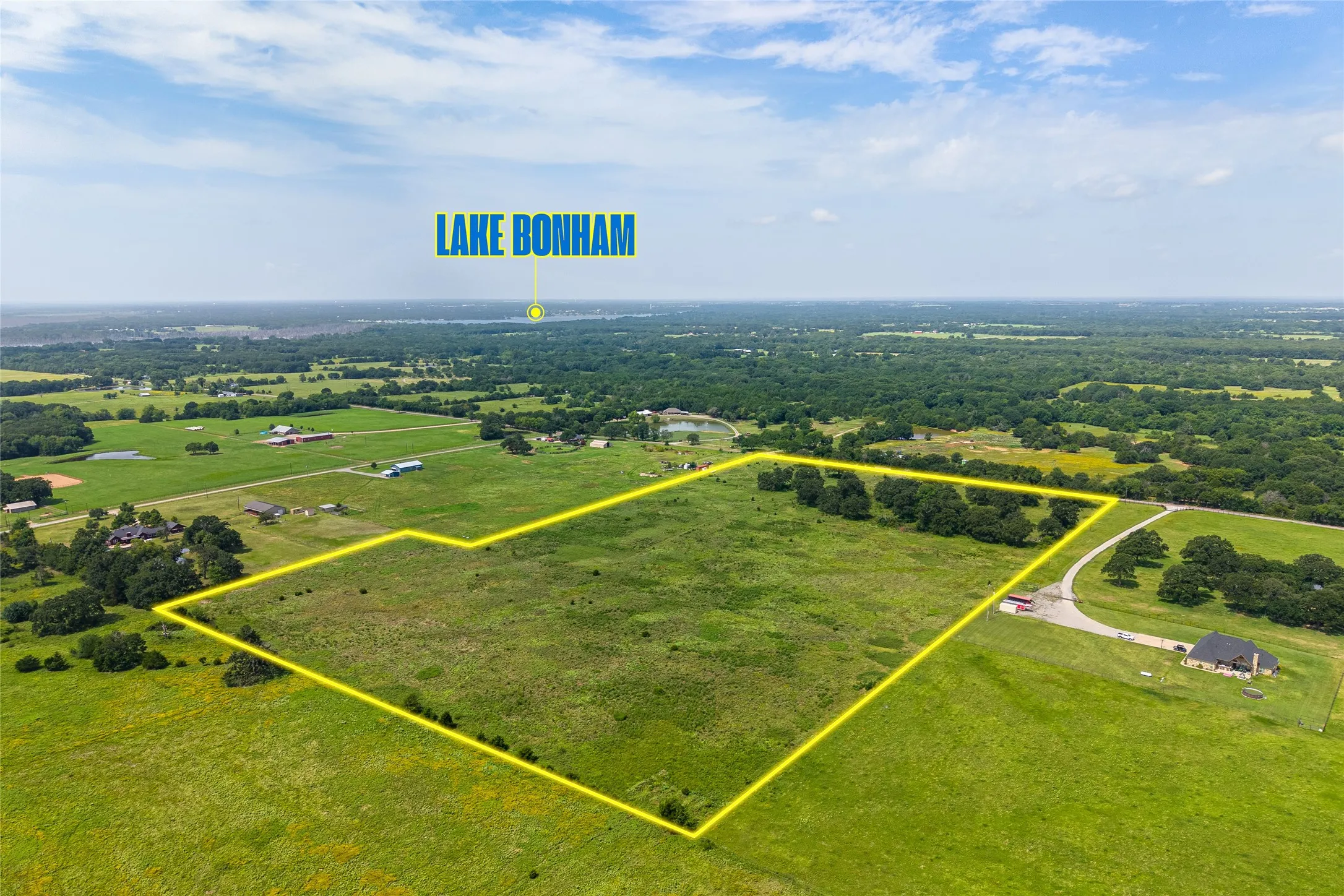 Aerial shot of 27+ acres with mature trees, pond, and open pasture looking NE