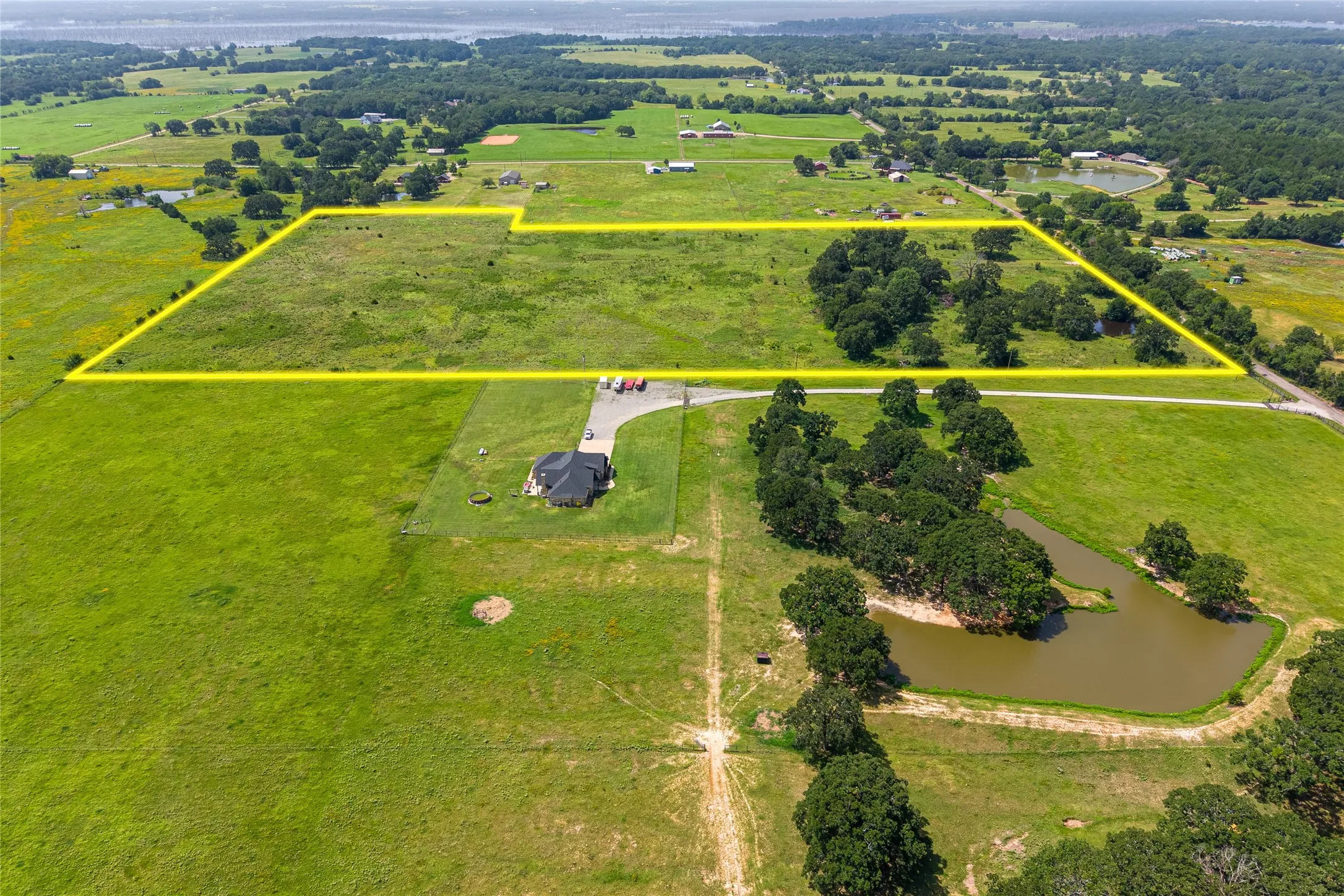 Aerial shot of 27+ acres with mature trees, pond, and open pasture looking N
