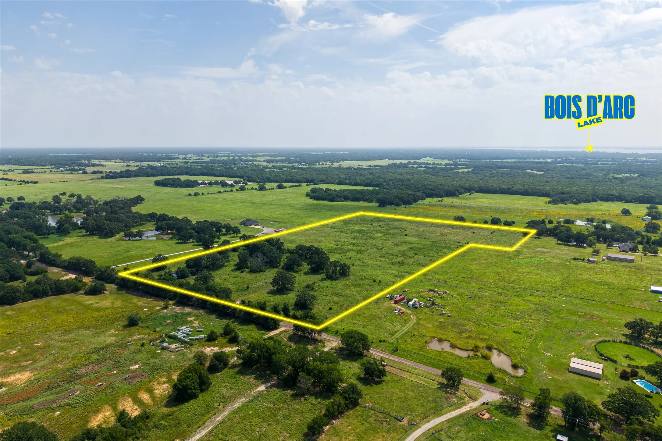 Aerial shot of 27+ acres with mature trees, pond, and open pasture looking SW