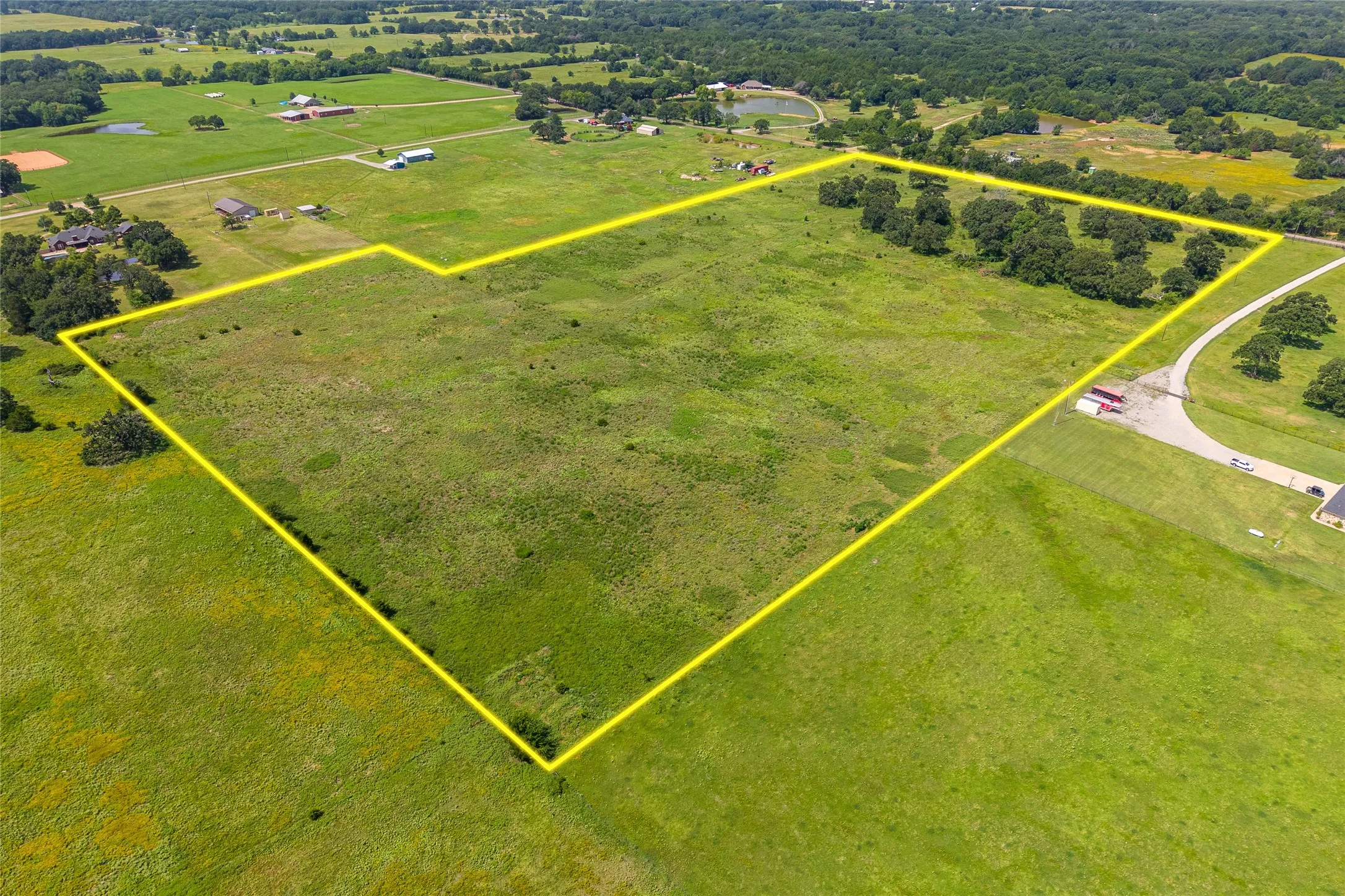 Aerial shot of 27+ acres with mature trees, pond, and open pasture looking NE