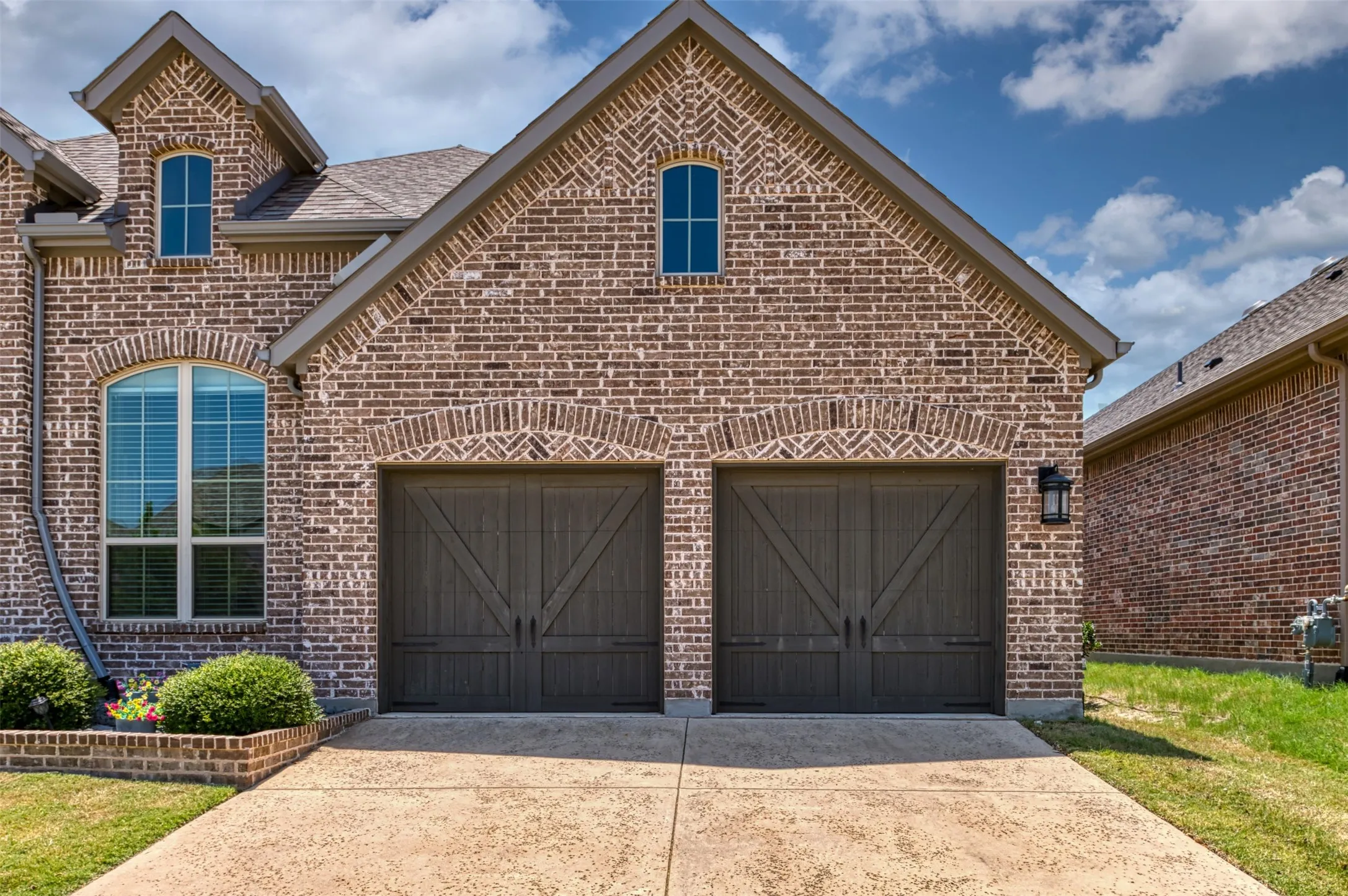 Brick facade with arched window and two carriage-style garage doors