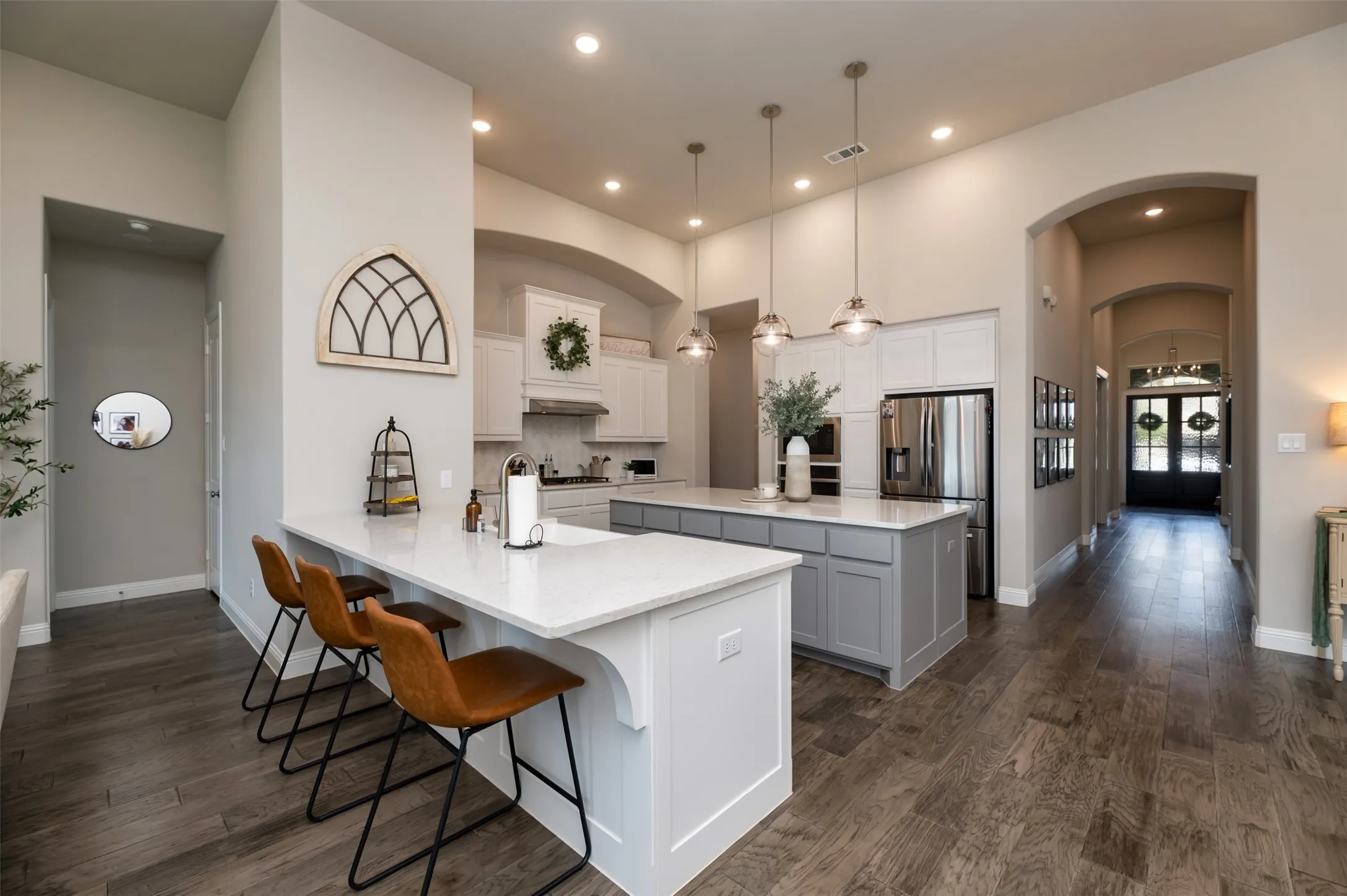 Open-concept kitchen featuring an eat-at island with a quartz countertop, recessed lighting, wood-finish flooring, and arched doorways