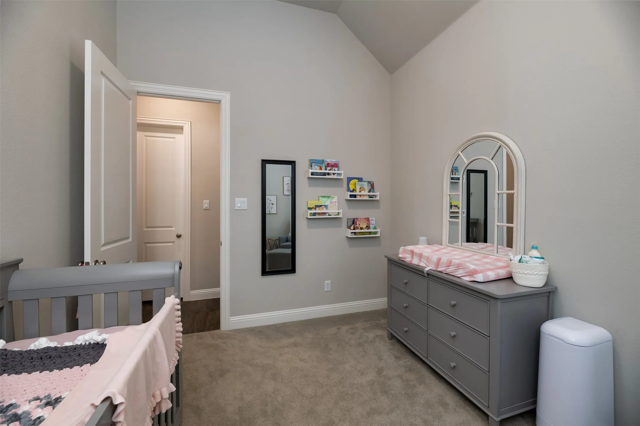 Interior room featuring vaulted ceilings, light gray wall paint, and gray carpet flooring