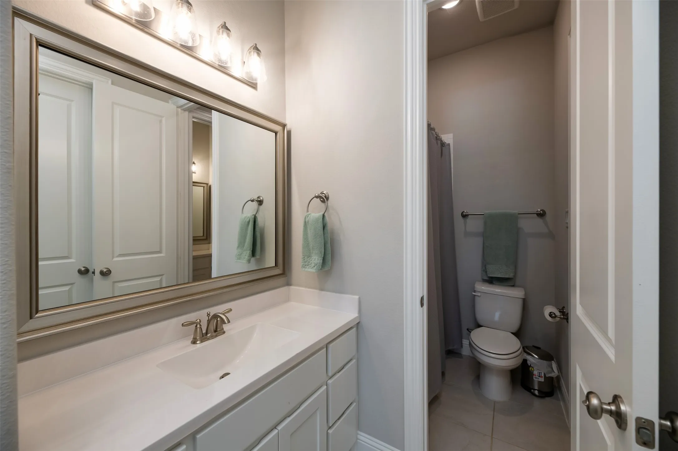 Bathroom vanity featuring a single integrated sink, light-toned countertop, and white cabinetry- jack and jill bathroom