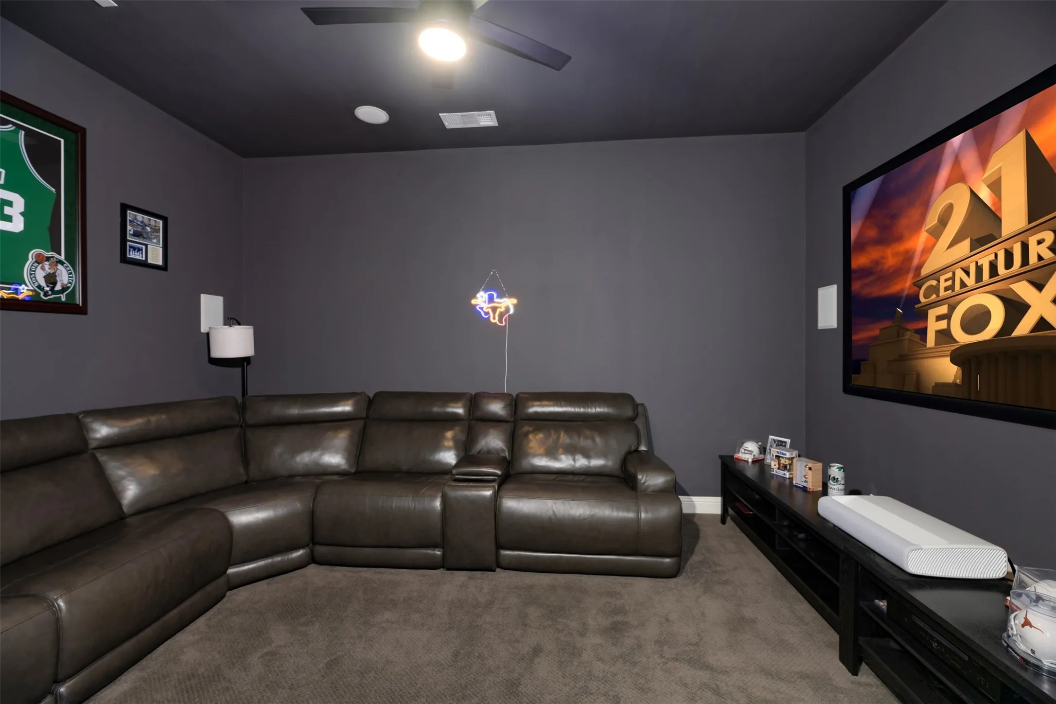 Dedicated media room featuring a large wall-mounted screen, dark gray walls, recessed lighting, and a ceiling fan