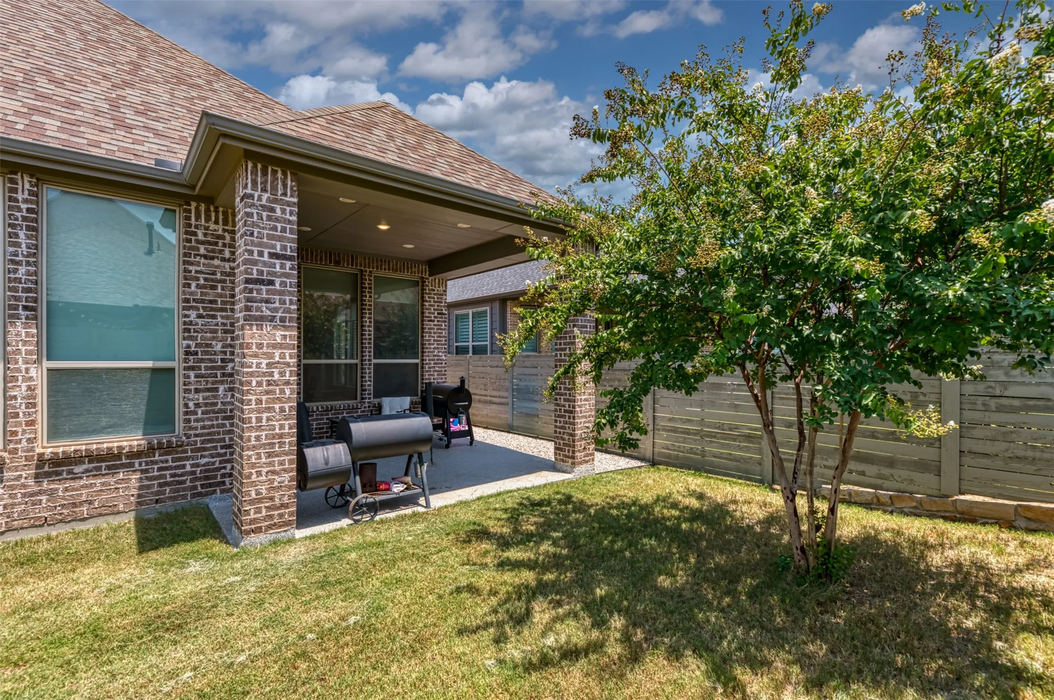 Covered patio featuring a concrete surface, brick support columns, and an exterior brick wall
