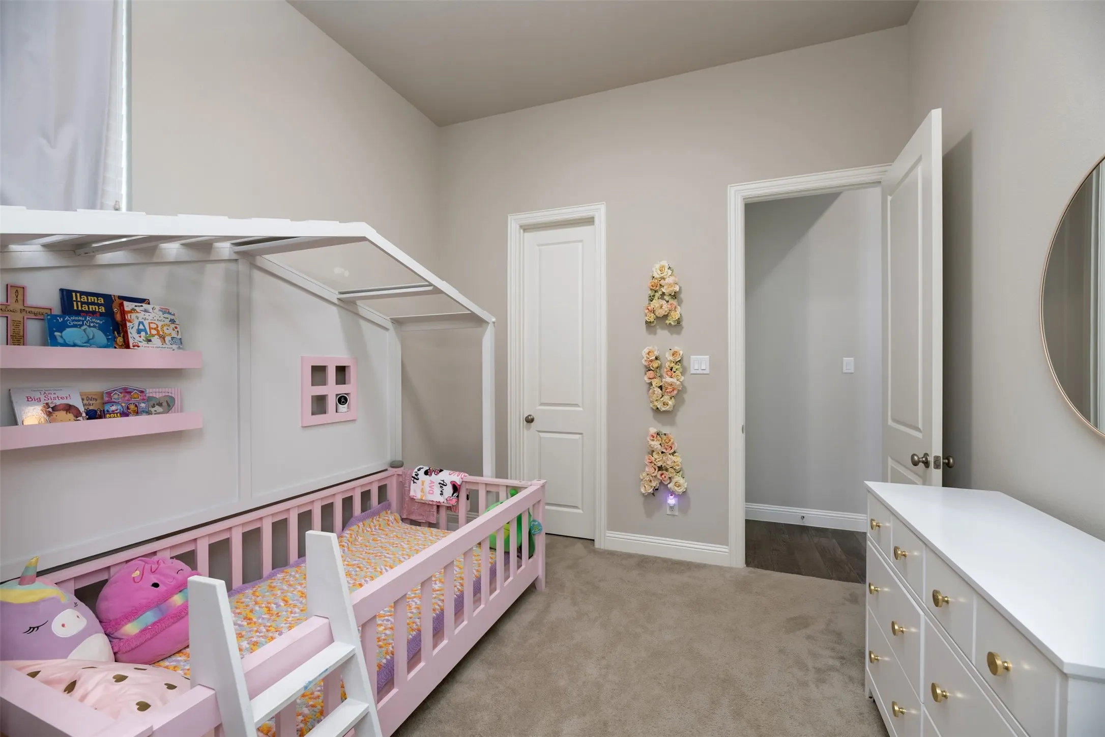 Carpeted room featuring light gray walls, white trim, and a white six-drawer dresser with gold-toned hardware