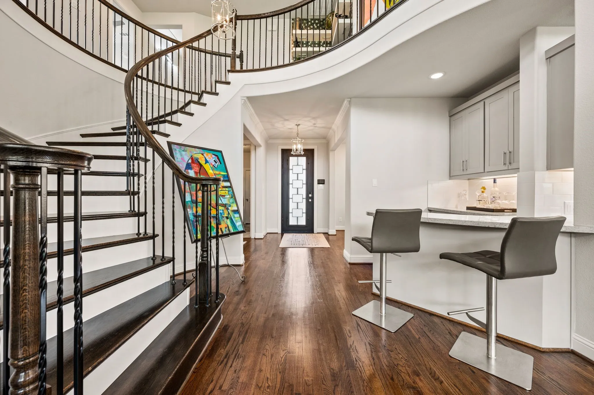 Wood floors continue up the stairs into the main areas of the second floor; Iron spindles; Gorgeous front custom door seen from this angle
