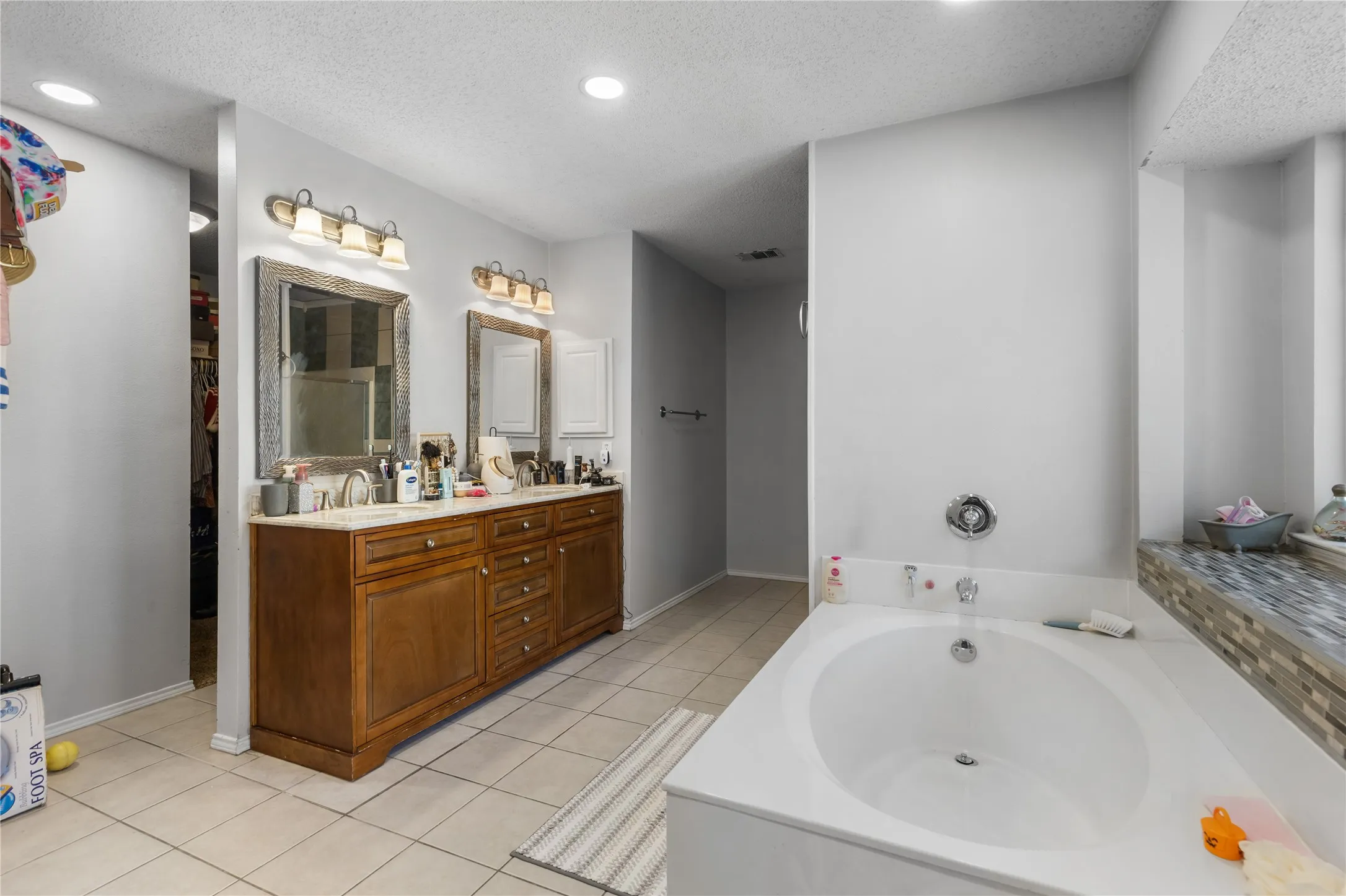 Dual vanity with wood cabinetry and undermount sinks, illuminated by two sets of wall-mounted light fixtures