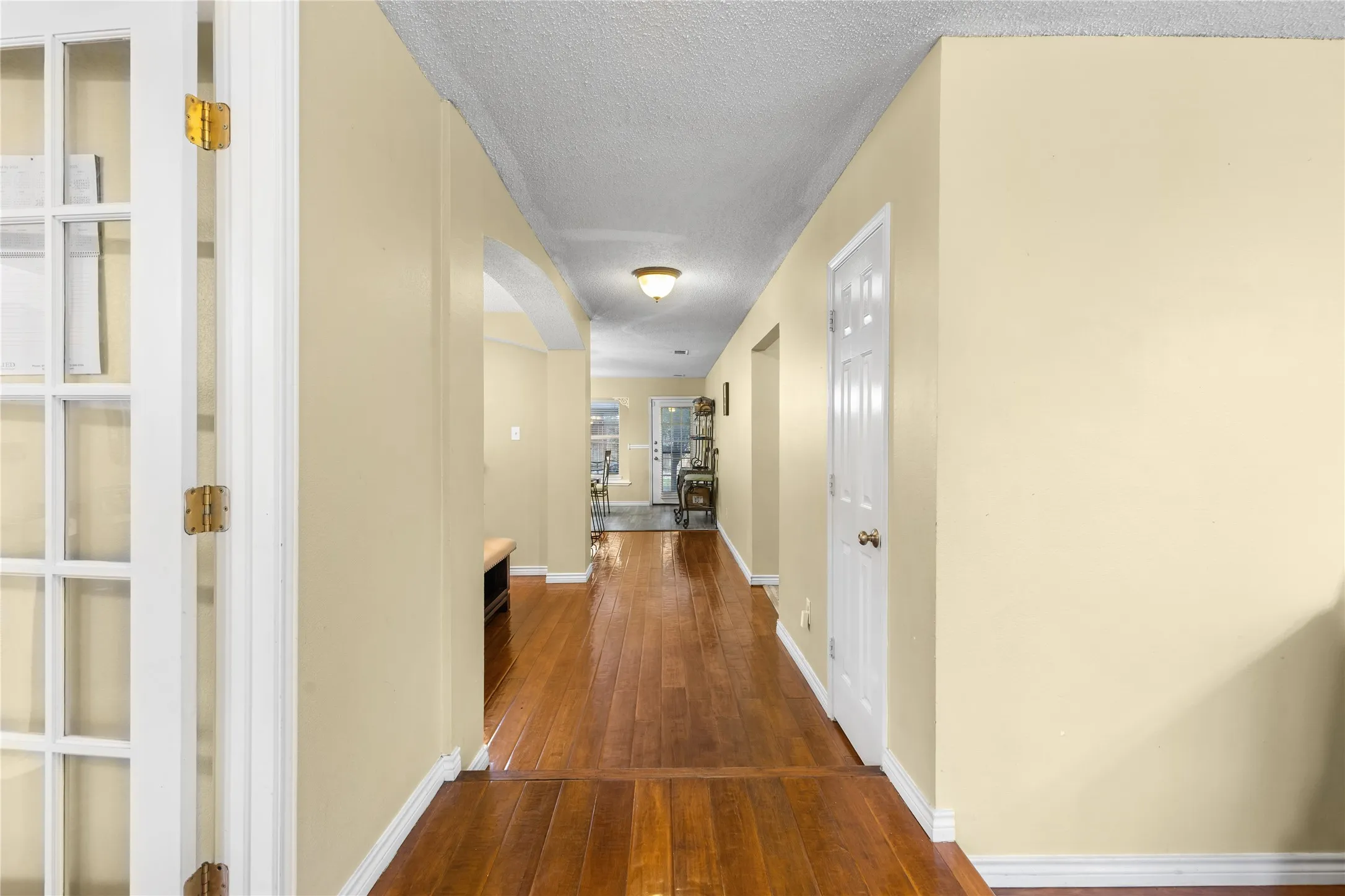 Hallway featuring wood-finish flooring, light-toned walls, white baseboards, and a ceiling-mounted light fixture