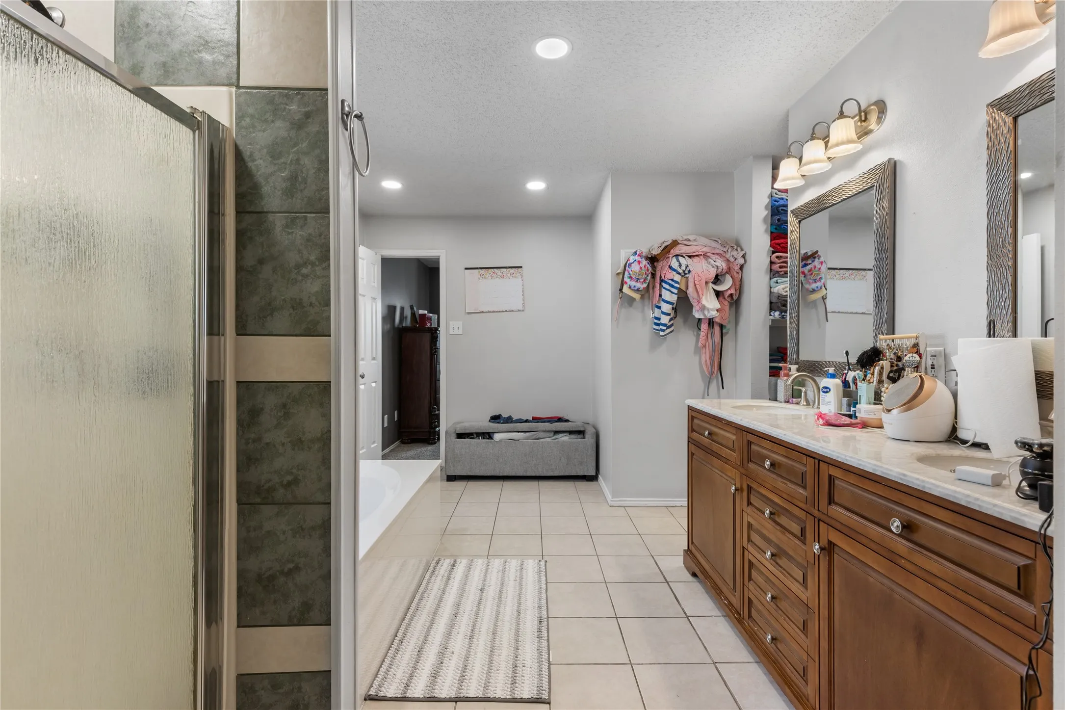 Bathroom featuring a dual vanity with a light-toned countertop, wood-finish cabinetry, and framed mirrors