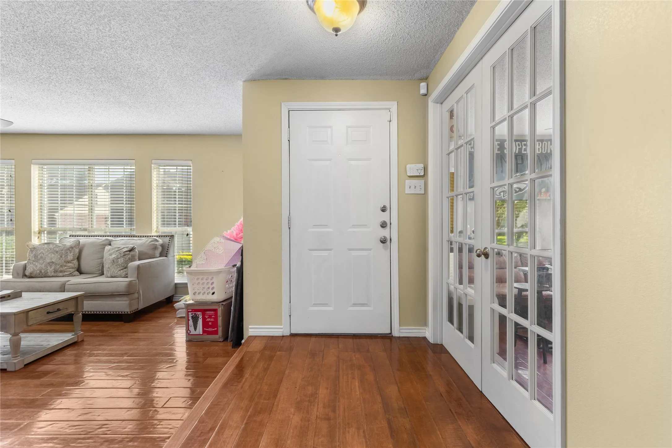 Entryway featuring rich wood-finish flooring, a white paneled door, and adjacent French doors with glass inserts